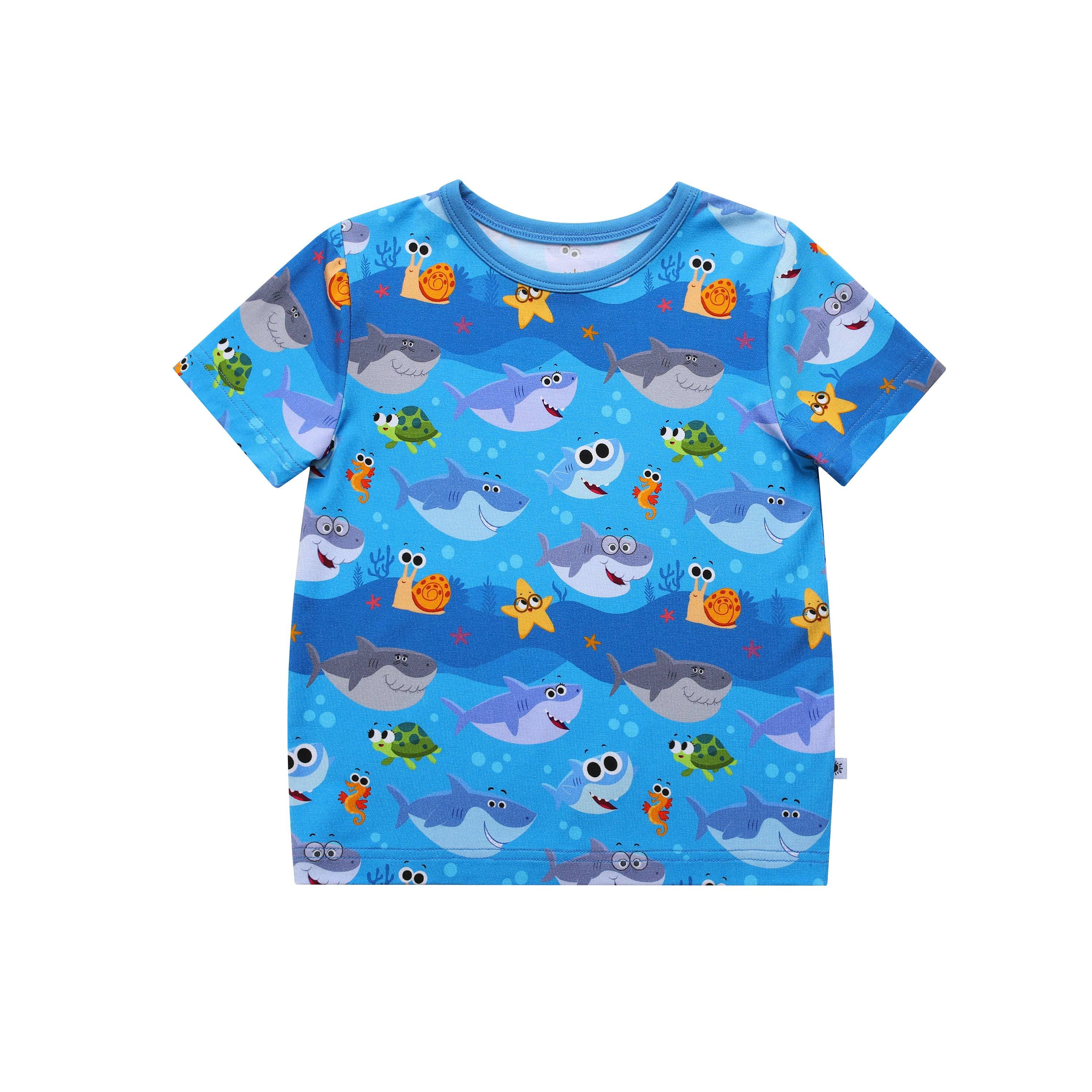 Blue t-shirt with a repeating pattern of cartoon sharks, turtles, starfish, seahorses, and snails.
