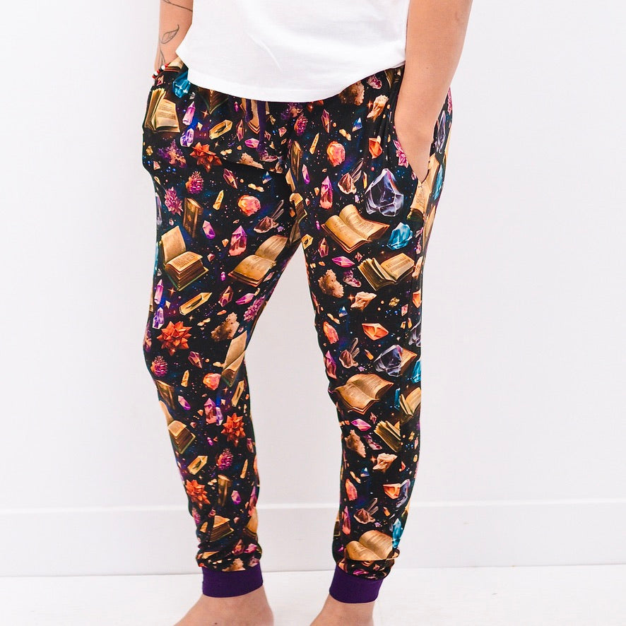 Womens bamboo joggers with a black background and a print of open books and colorful crystals.