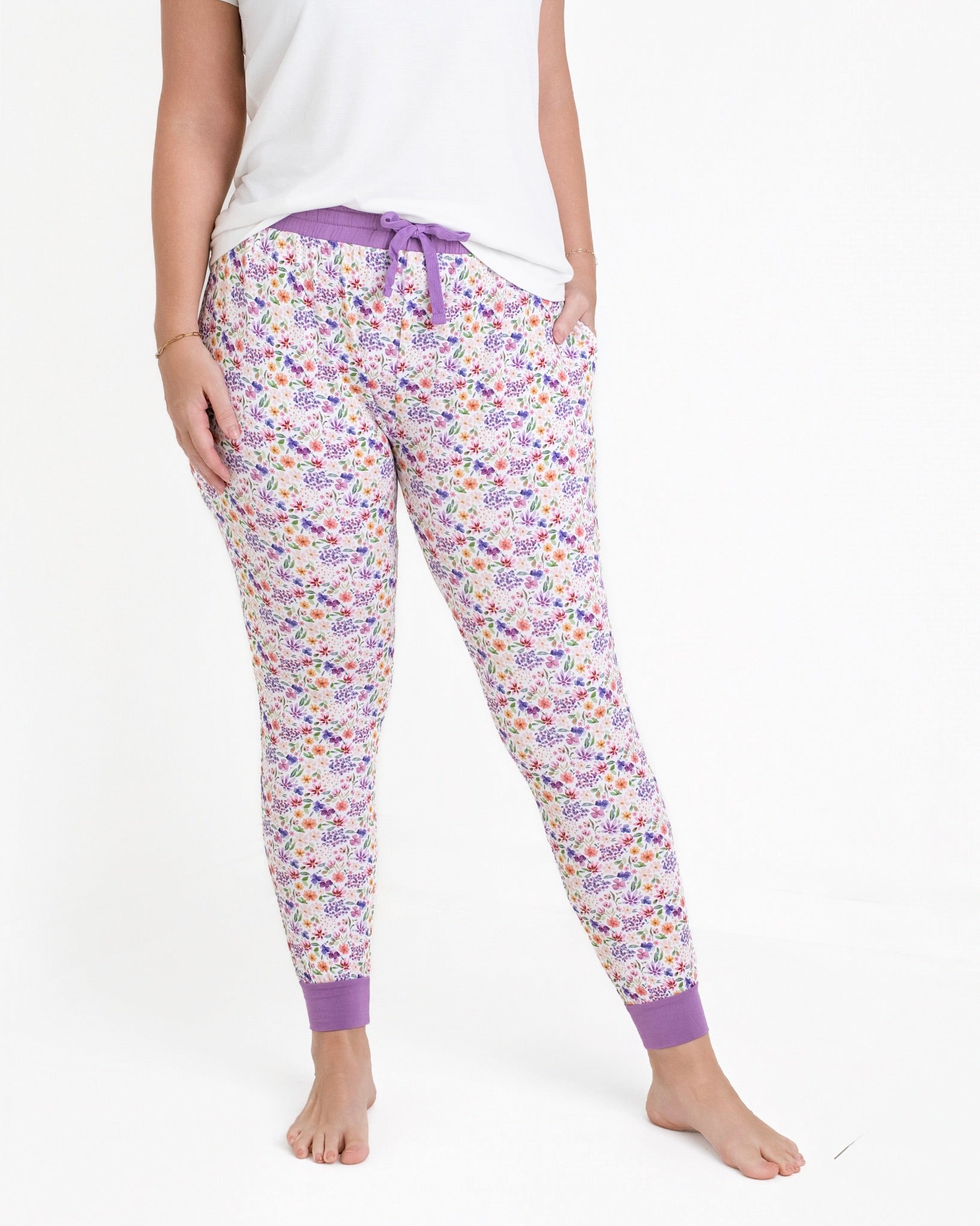 Women's floral print bamboo joggers with purple cuffs and drawstring.
