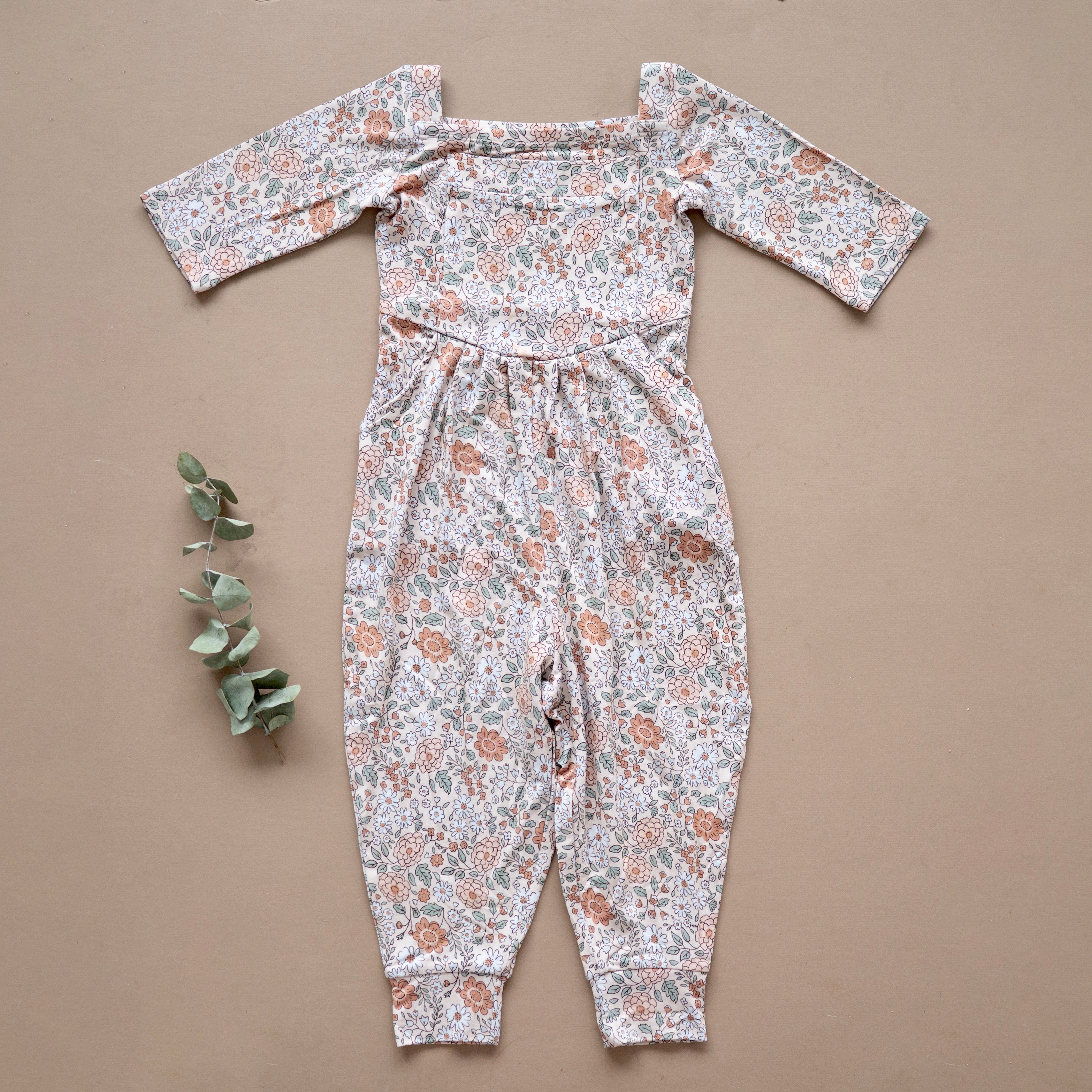 A floral print romper with a square neckline and cuffed legs.
