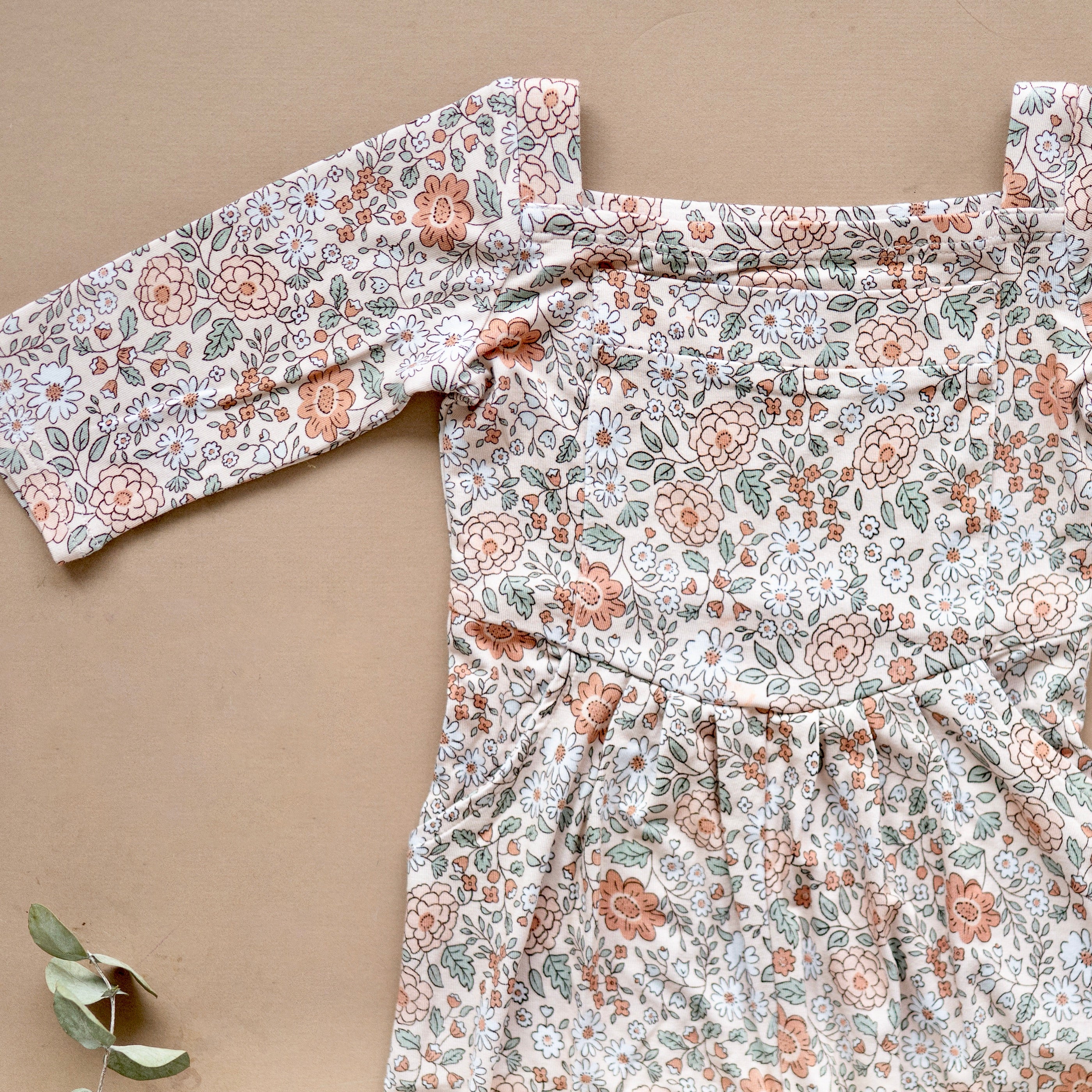 A light beige romper with a vintage floral print and square neckline.