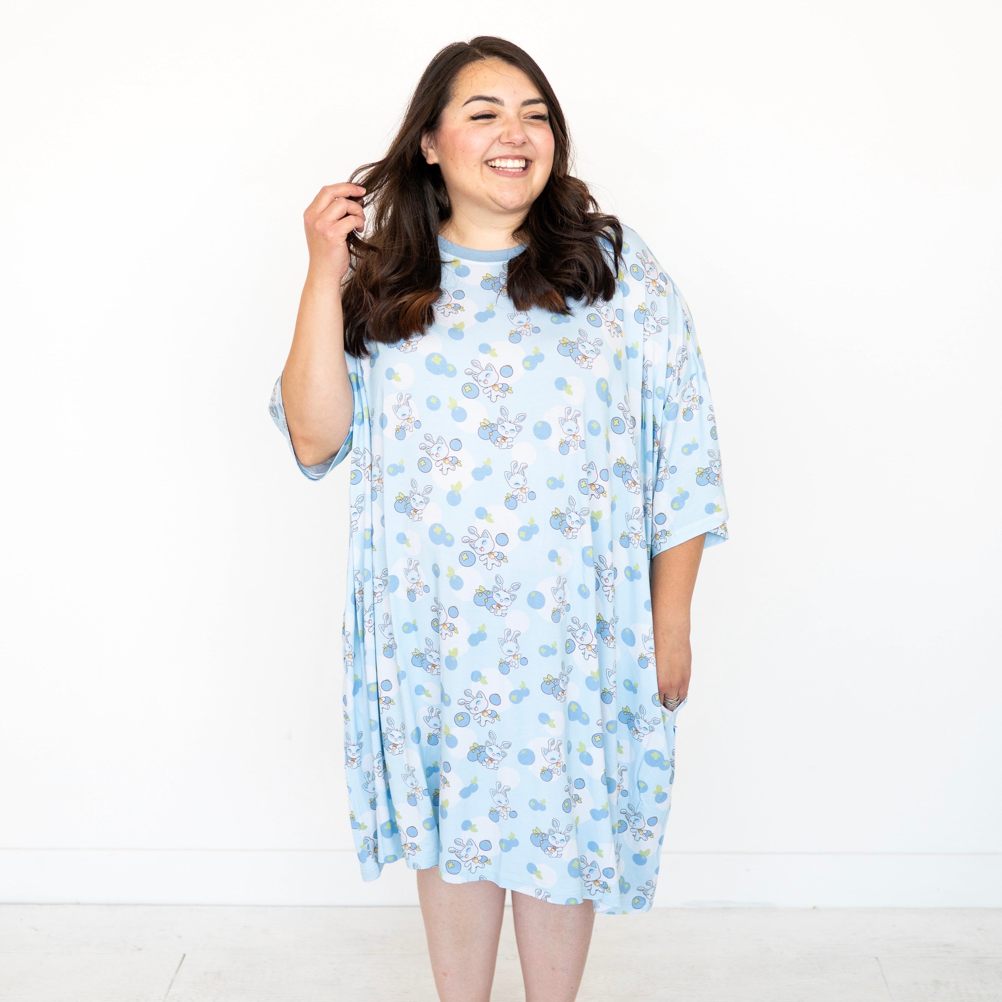 A woman wears a light blue Neopets blueberry baby print oversized sleep tee.