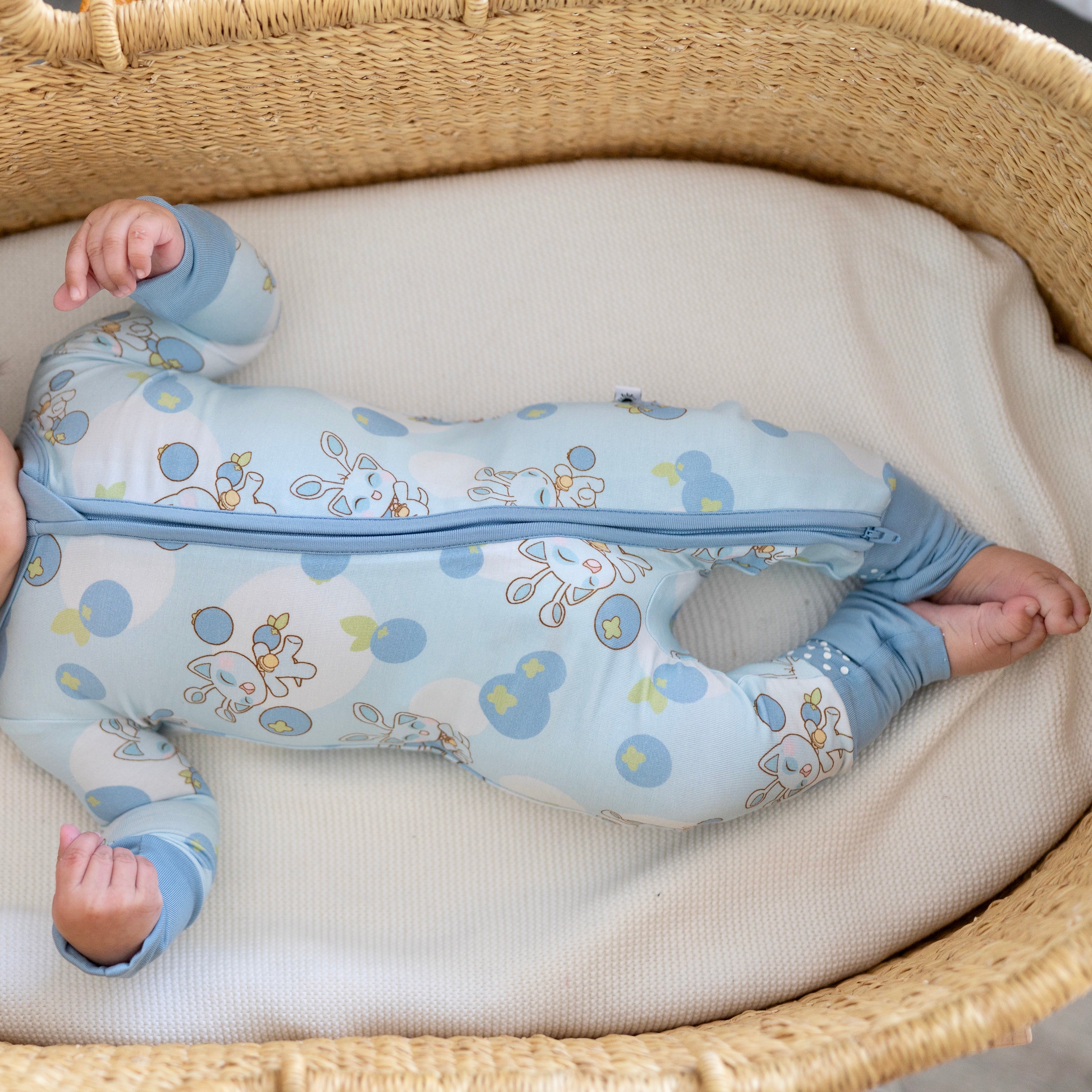 A baby wearing light blue pajamas with a blueberry and Neopets print.