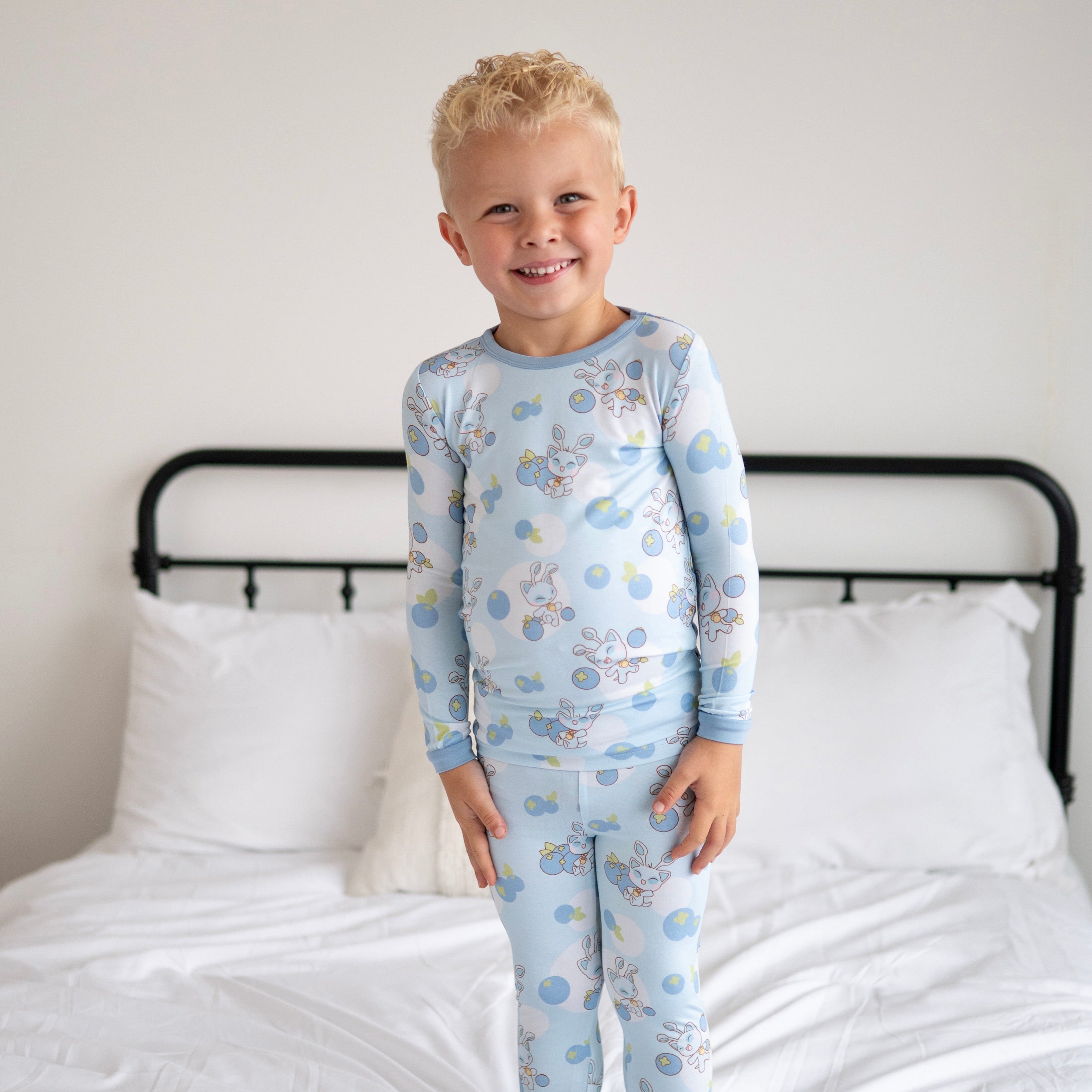 A young boy smiles in blue pajamas with a blueberry and bunny pattern.