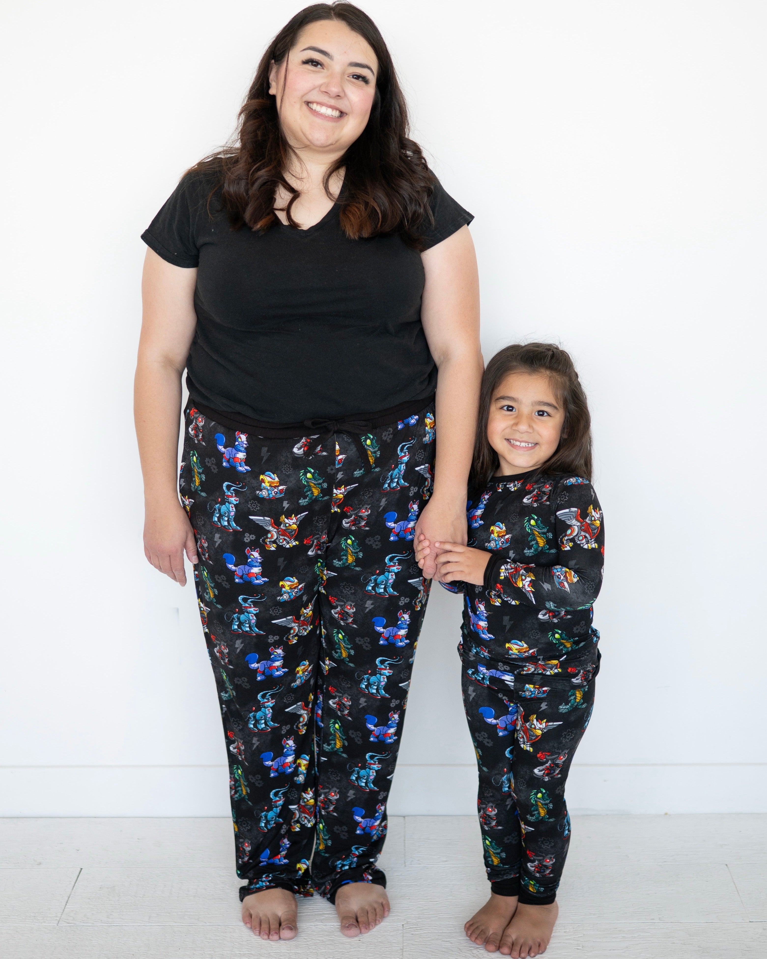 A woman and child in matching black pajamas with a Neopets robot print.