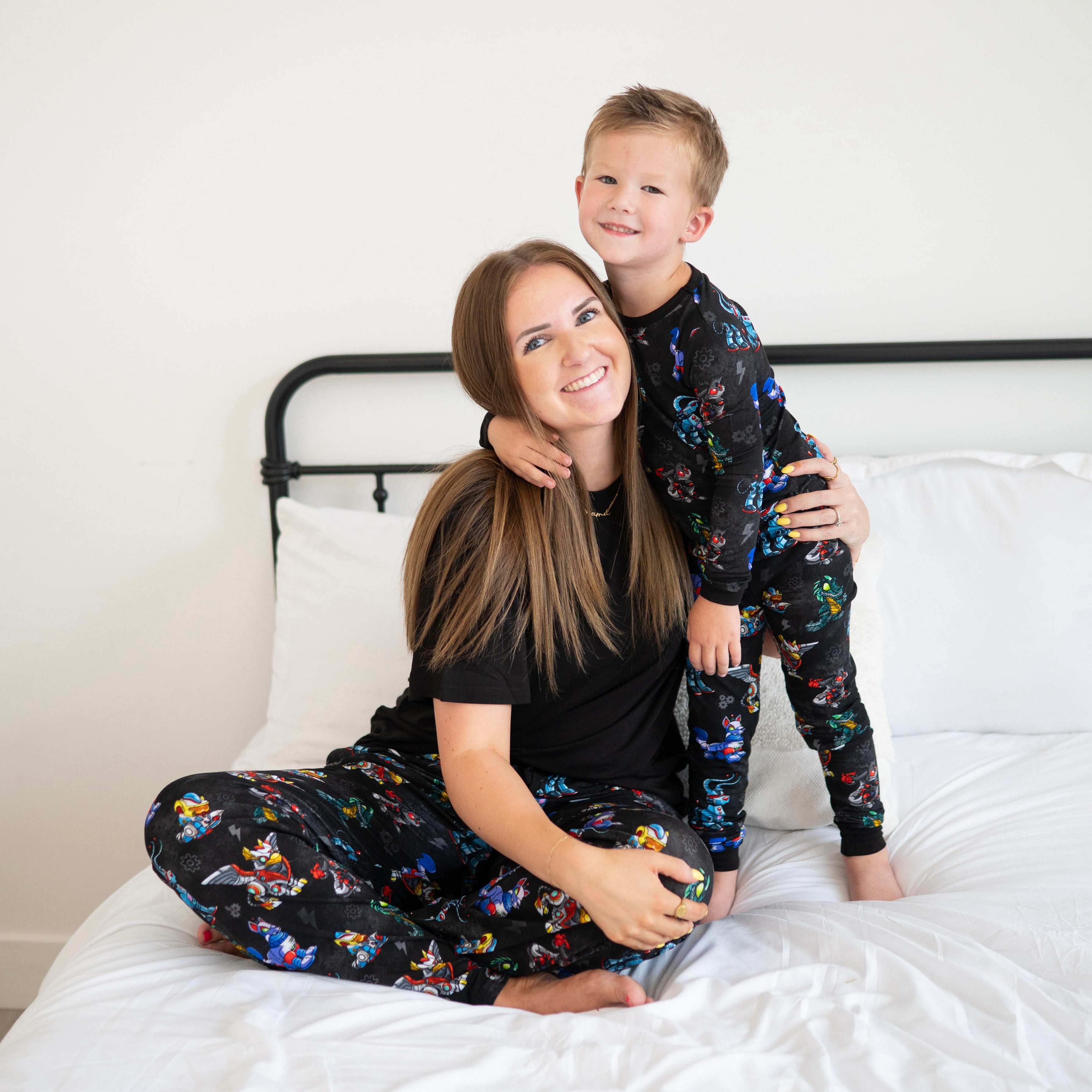 A woman and child in matching black pajamas with a Neopets robot print.