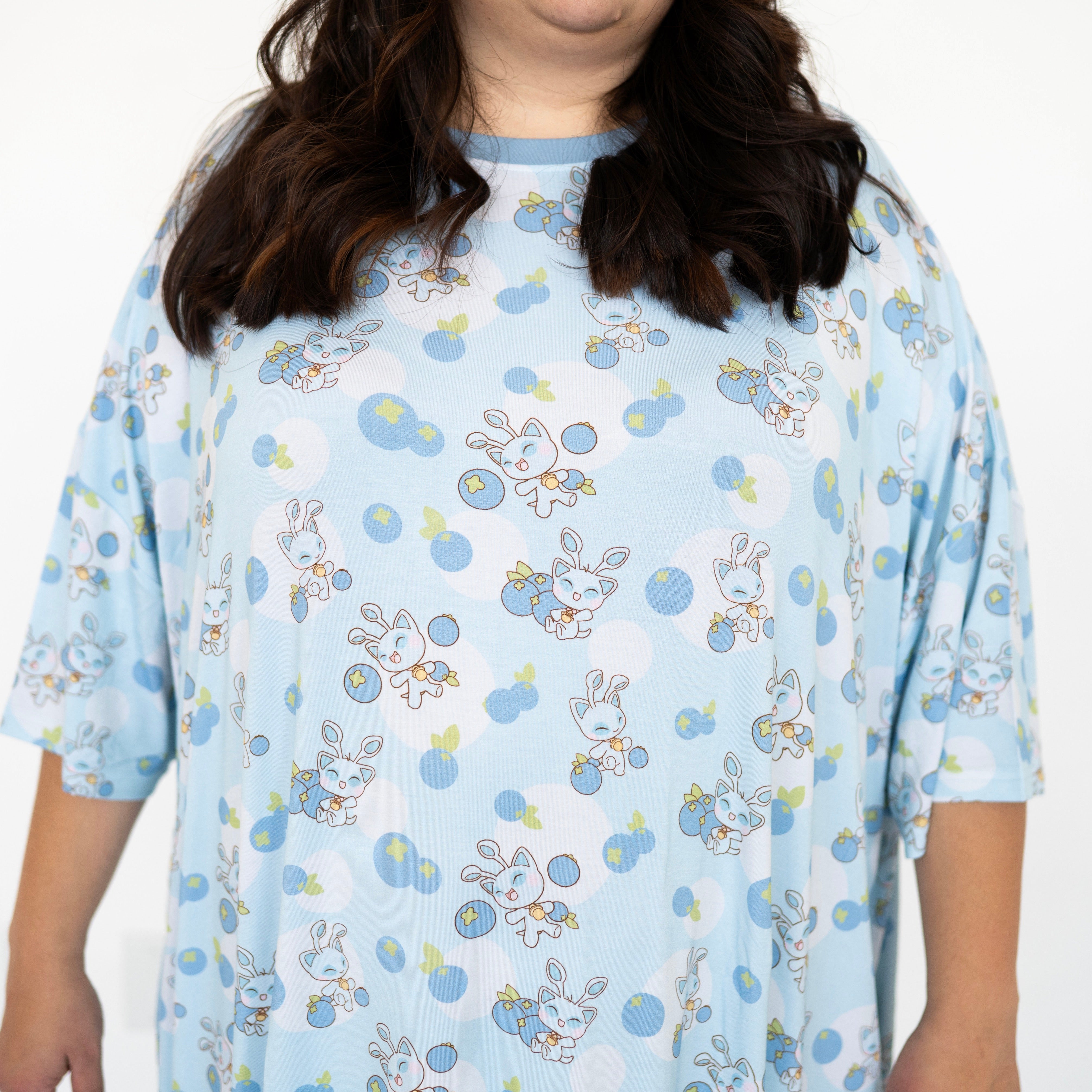 Adult Mega Sleep Tee with a light blue background and a repeating pattern of cute blue cat-like characters and blueberries.