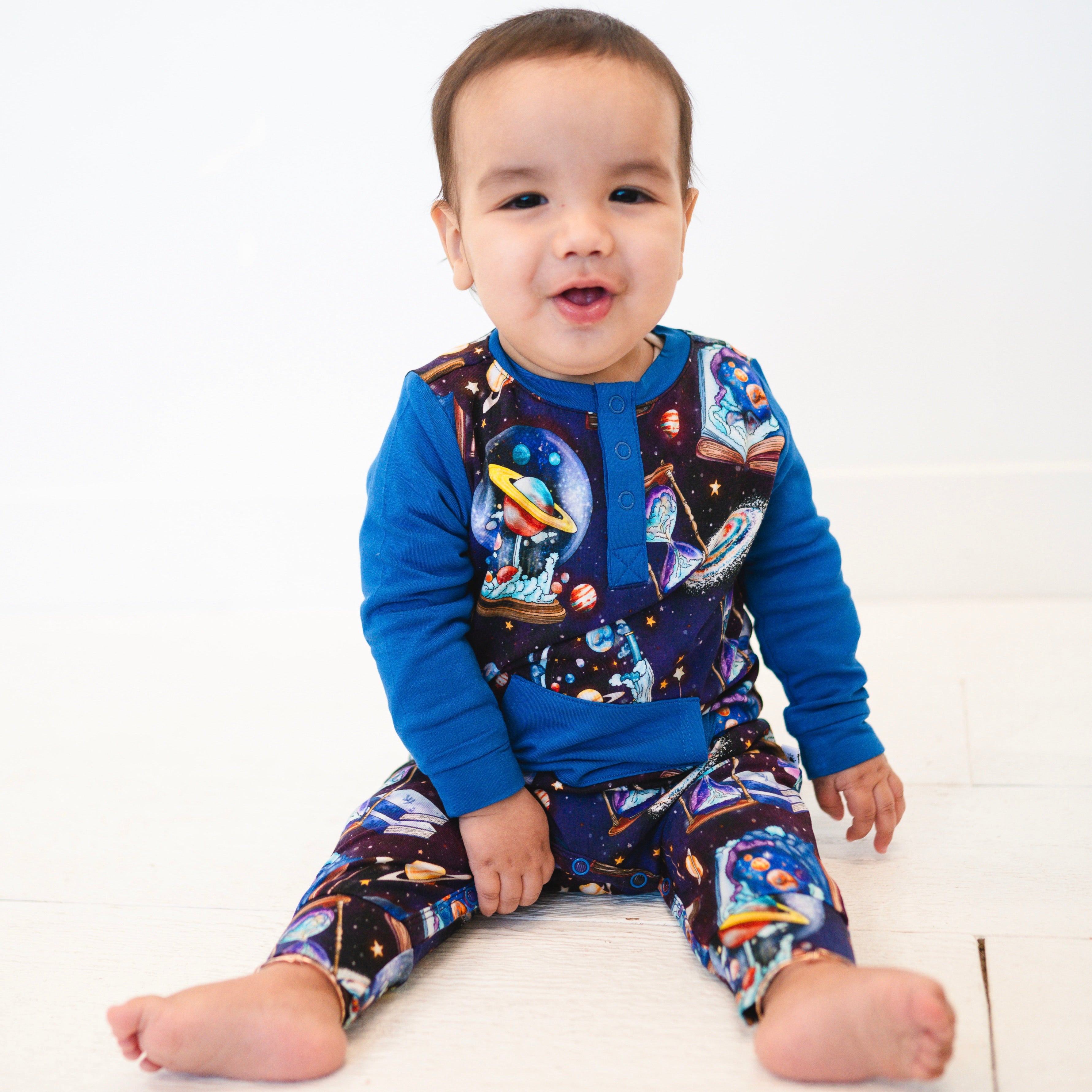 A baby wearing a blue and space-themed Henley romper.