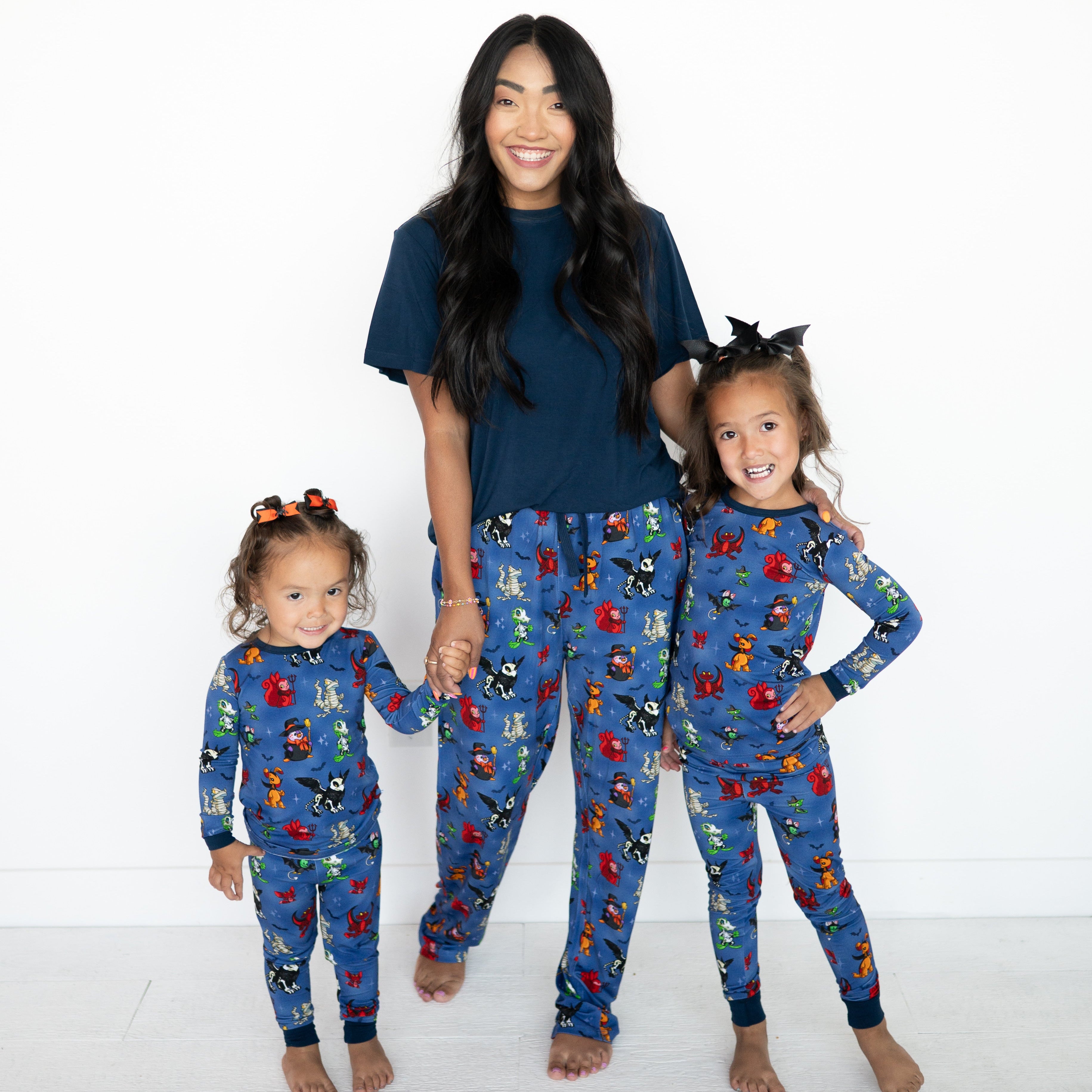 A woman and two children wear matching blue pajamas with a Halloween Neopets print.