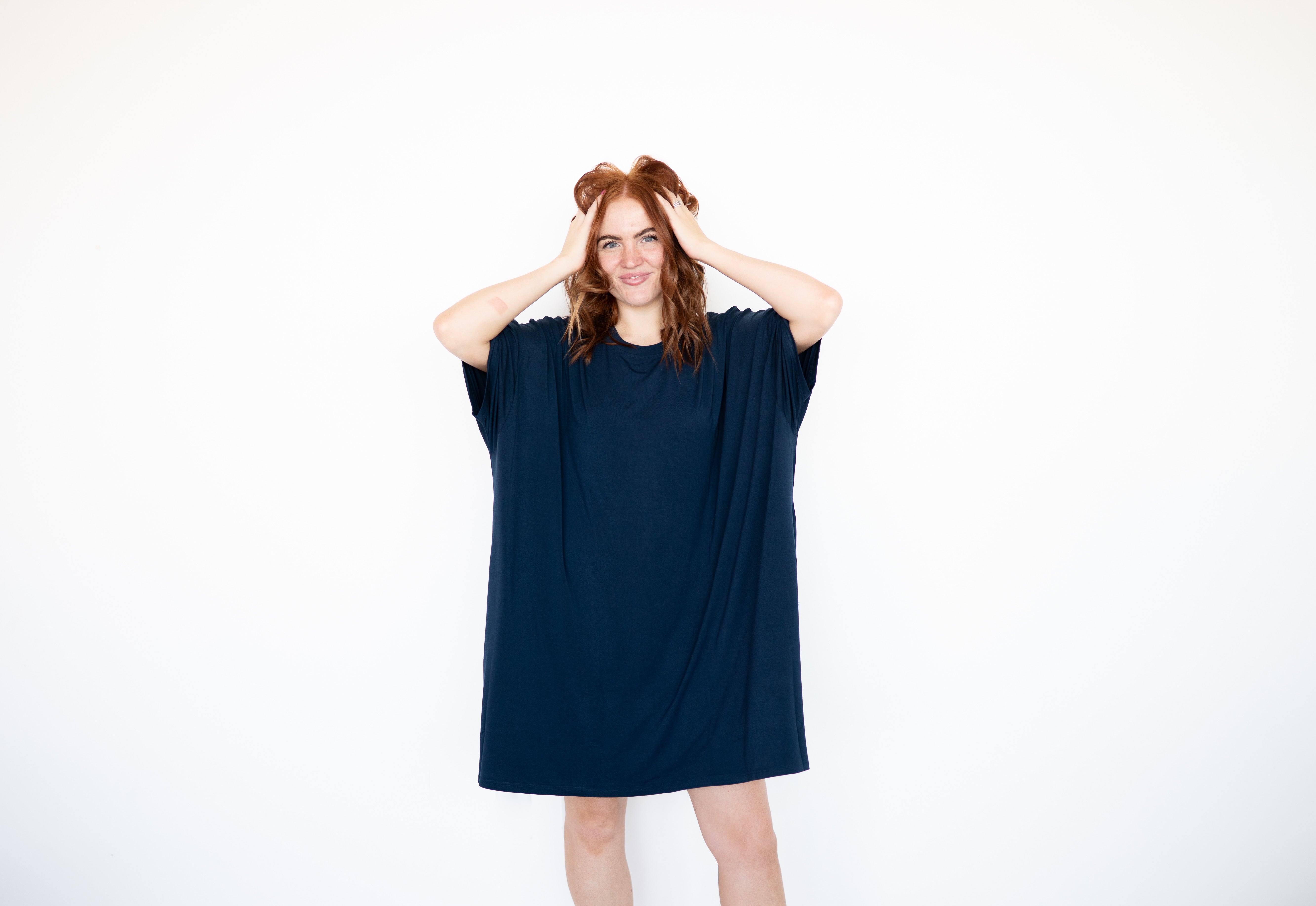 A woman in a navy blue oversized sleep shirt stands against a white background.