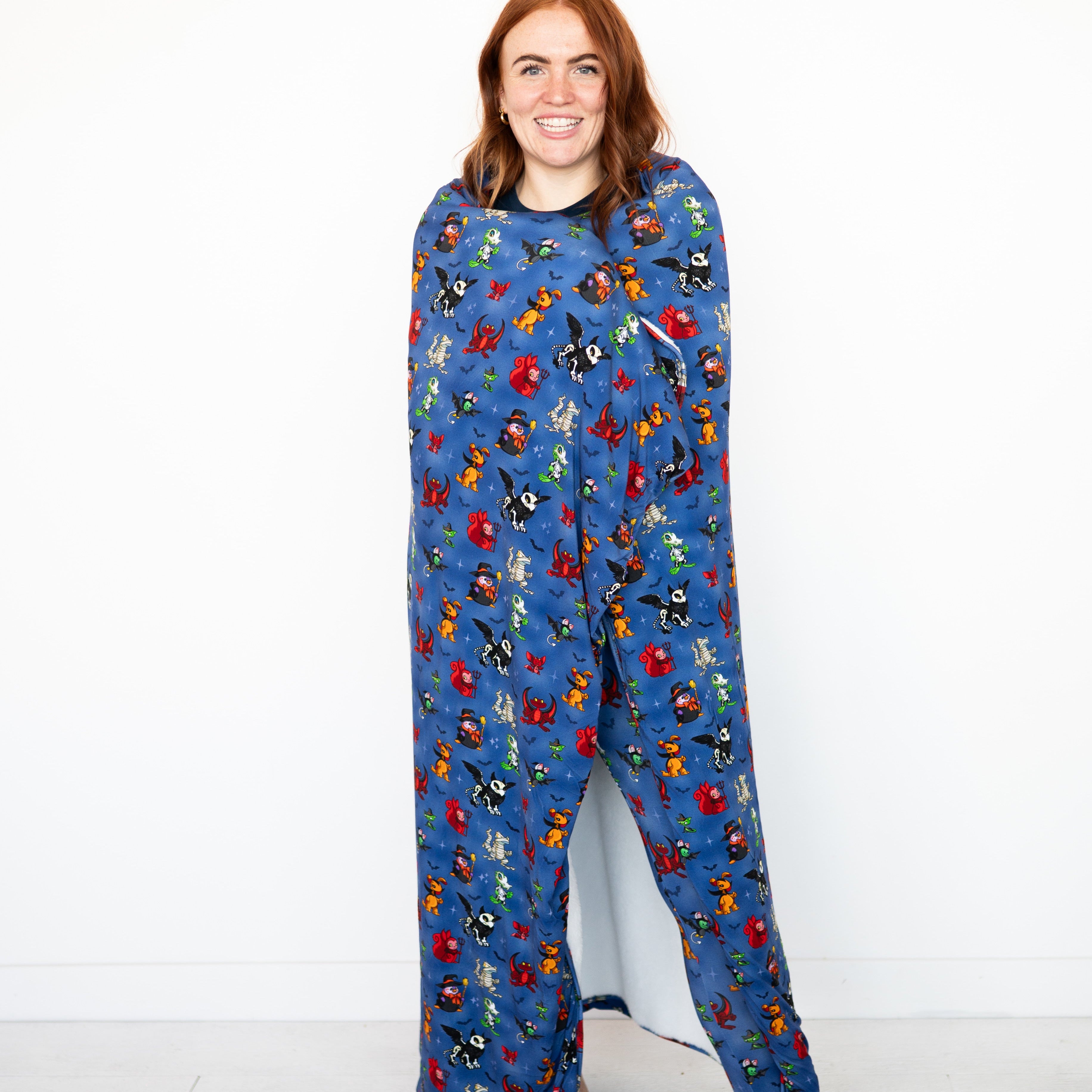 A woman wears a blue blanket with a Halloween Neopets print.
