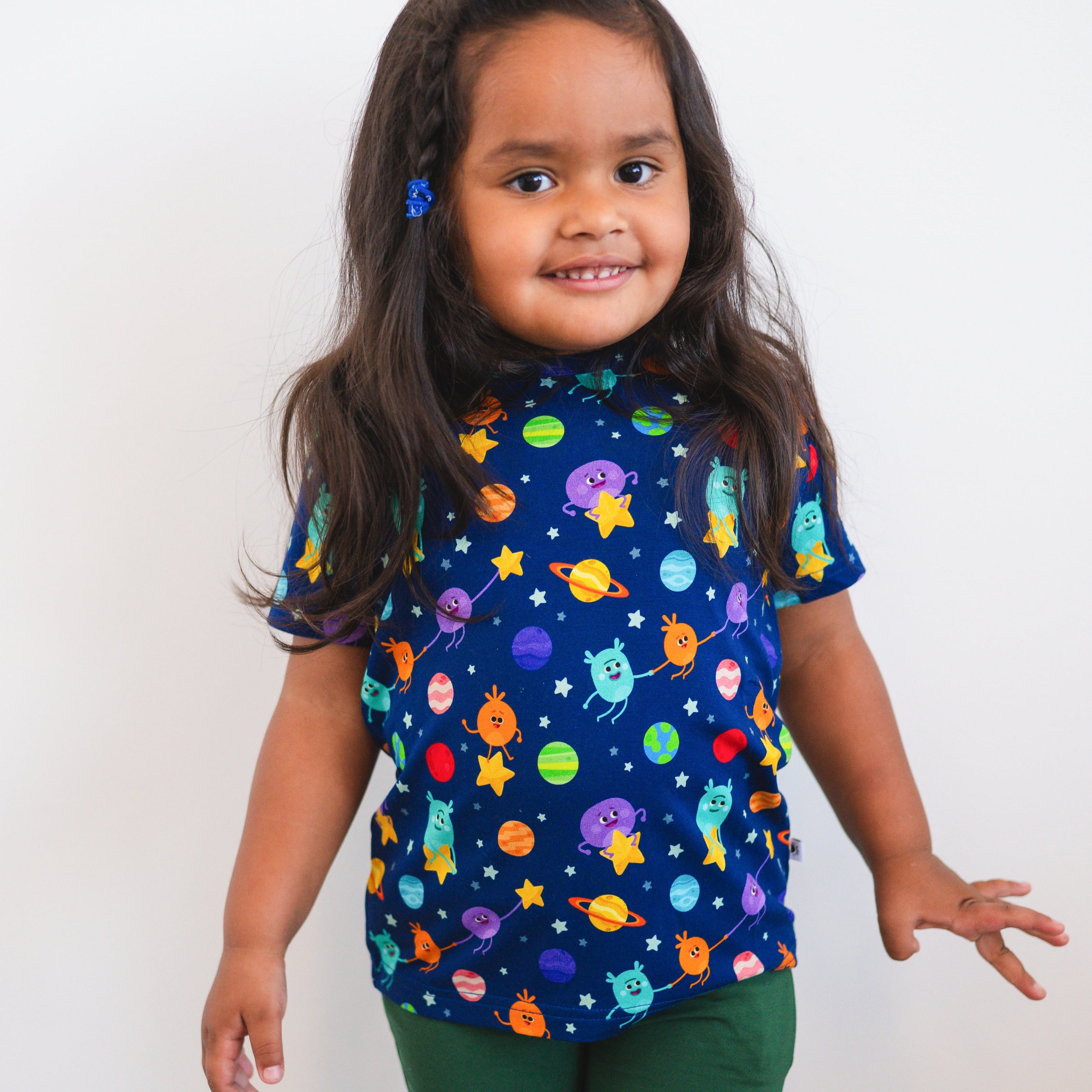 A young girl wears a dark blue t-shirt with a space-themed print.