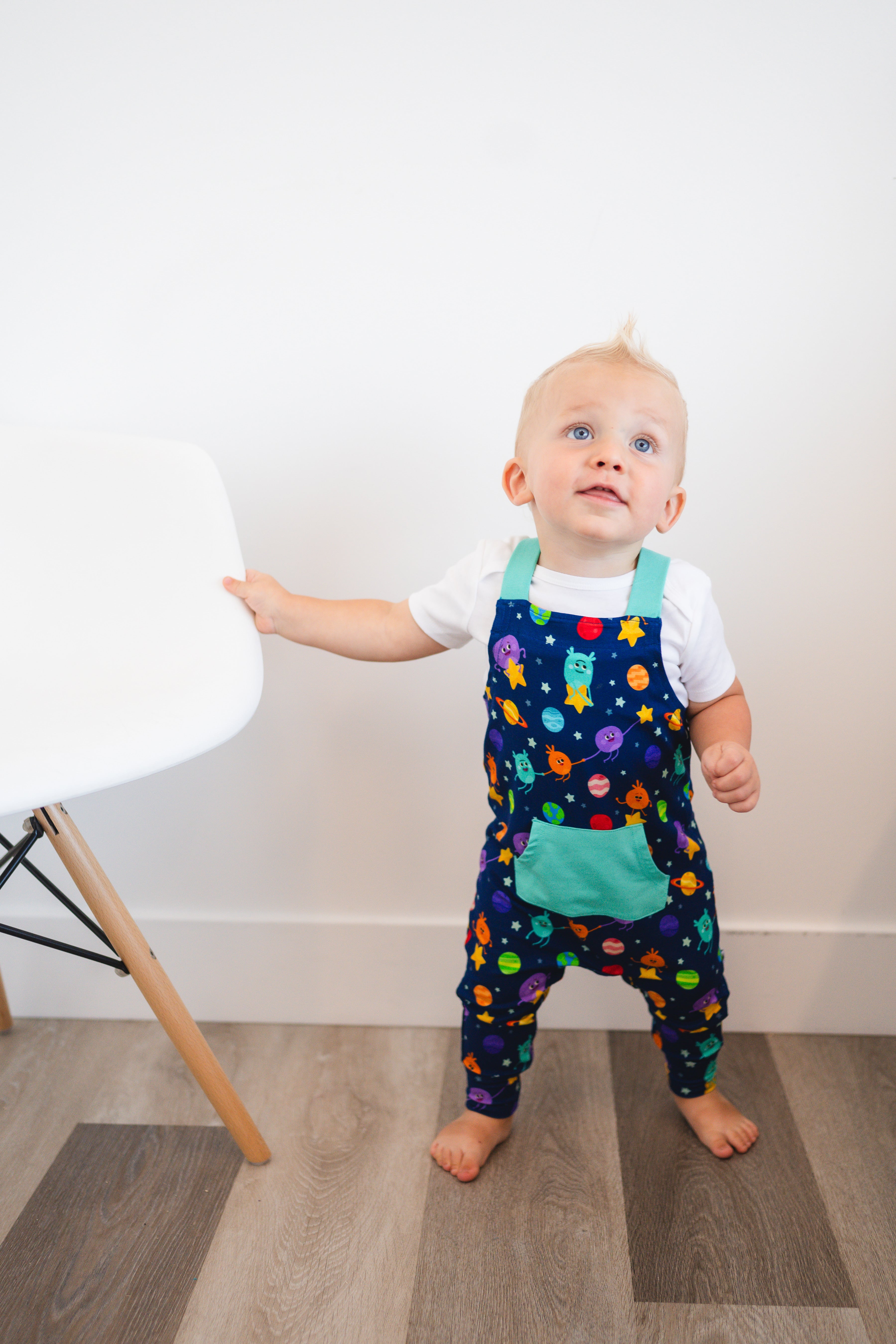 Toddler overalls with a space-themed print and teal accents.