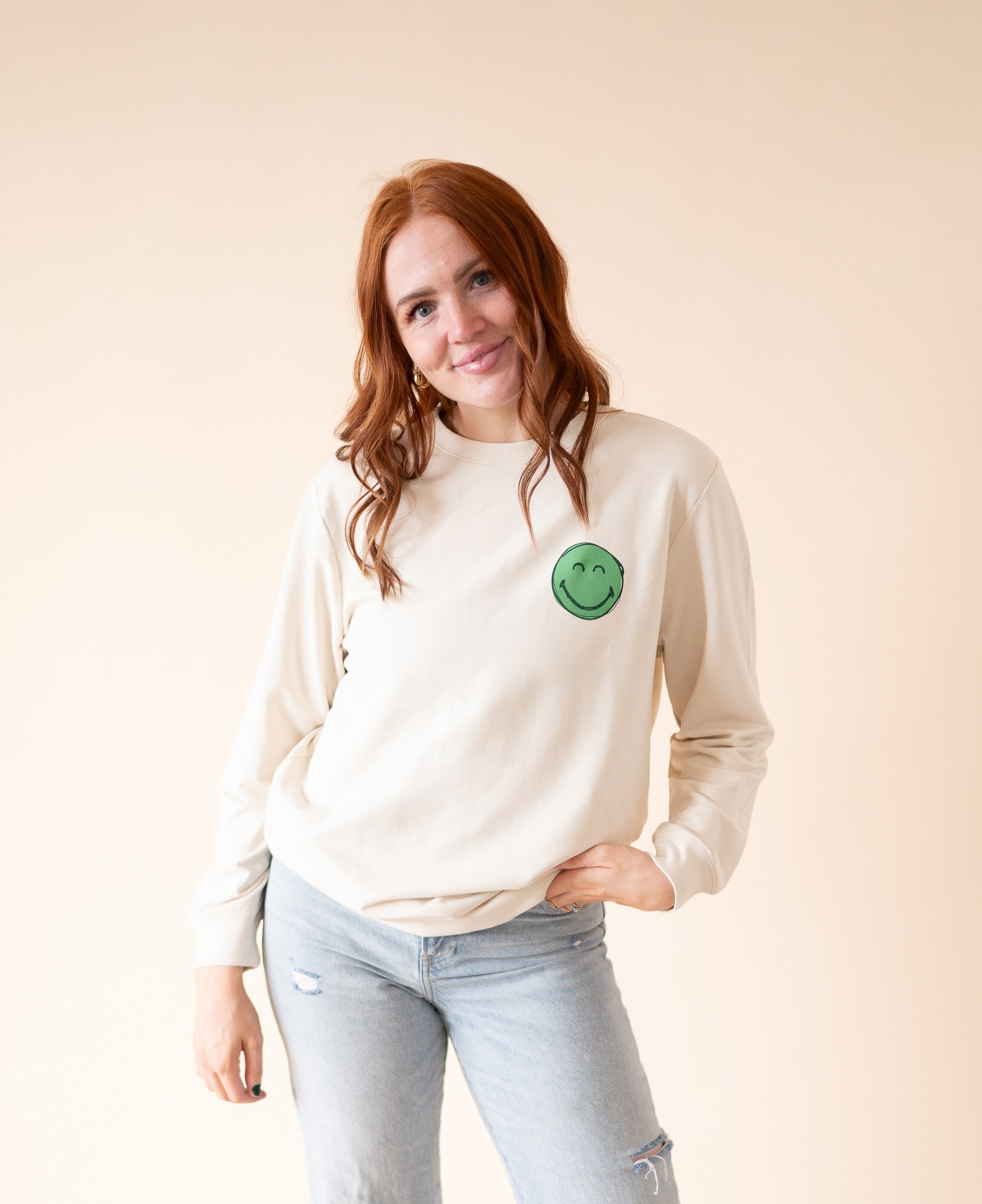 Adult unisex crewneck sweatshirt with a green smiley face graphic.