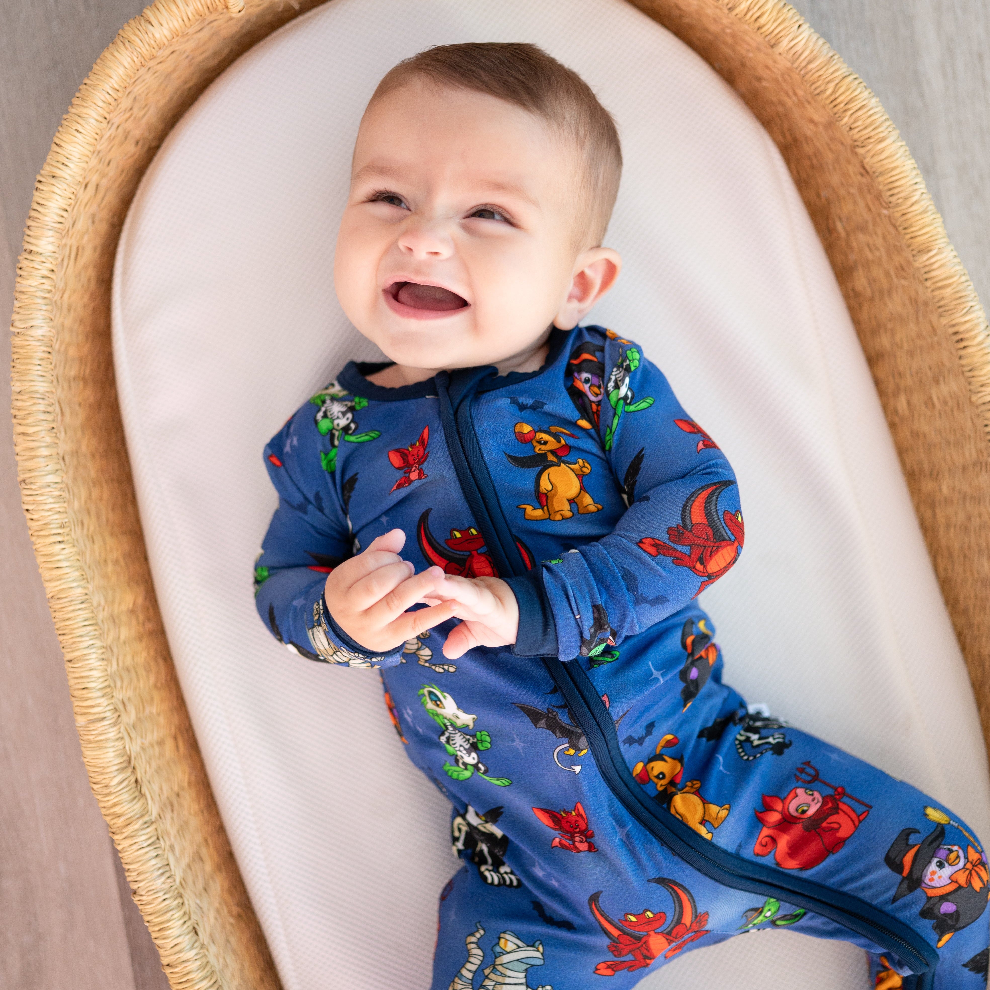 Baby in blue Halloween-themed Neopets pajamas in a wicker bassinet.
