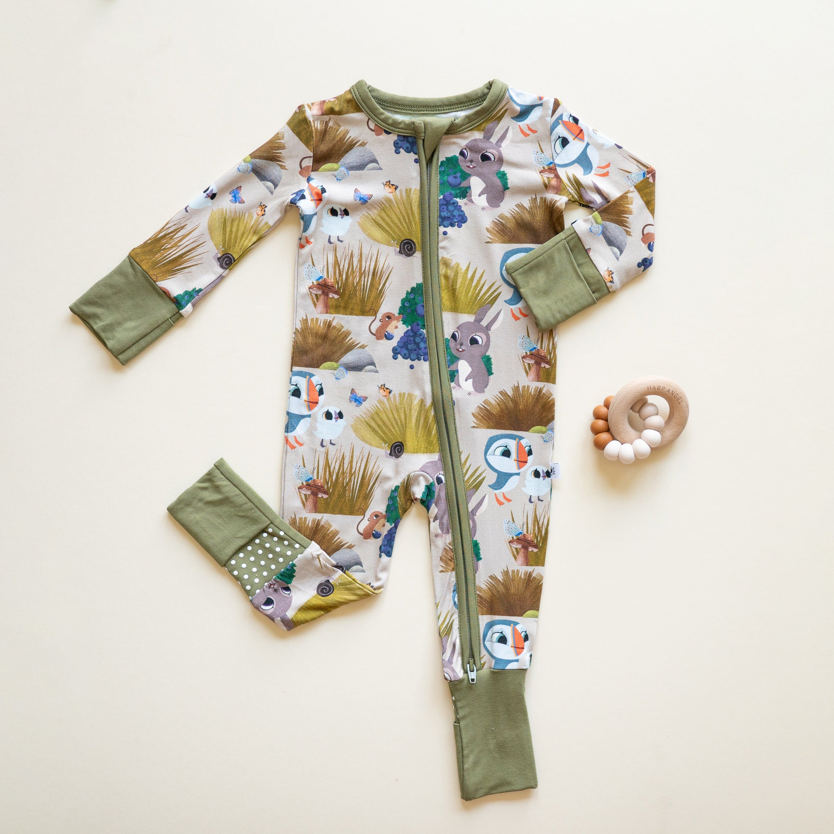 A baby's bamboo pajama set with a Puffin Rock print and a wooden teether.