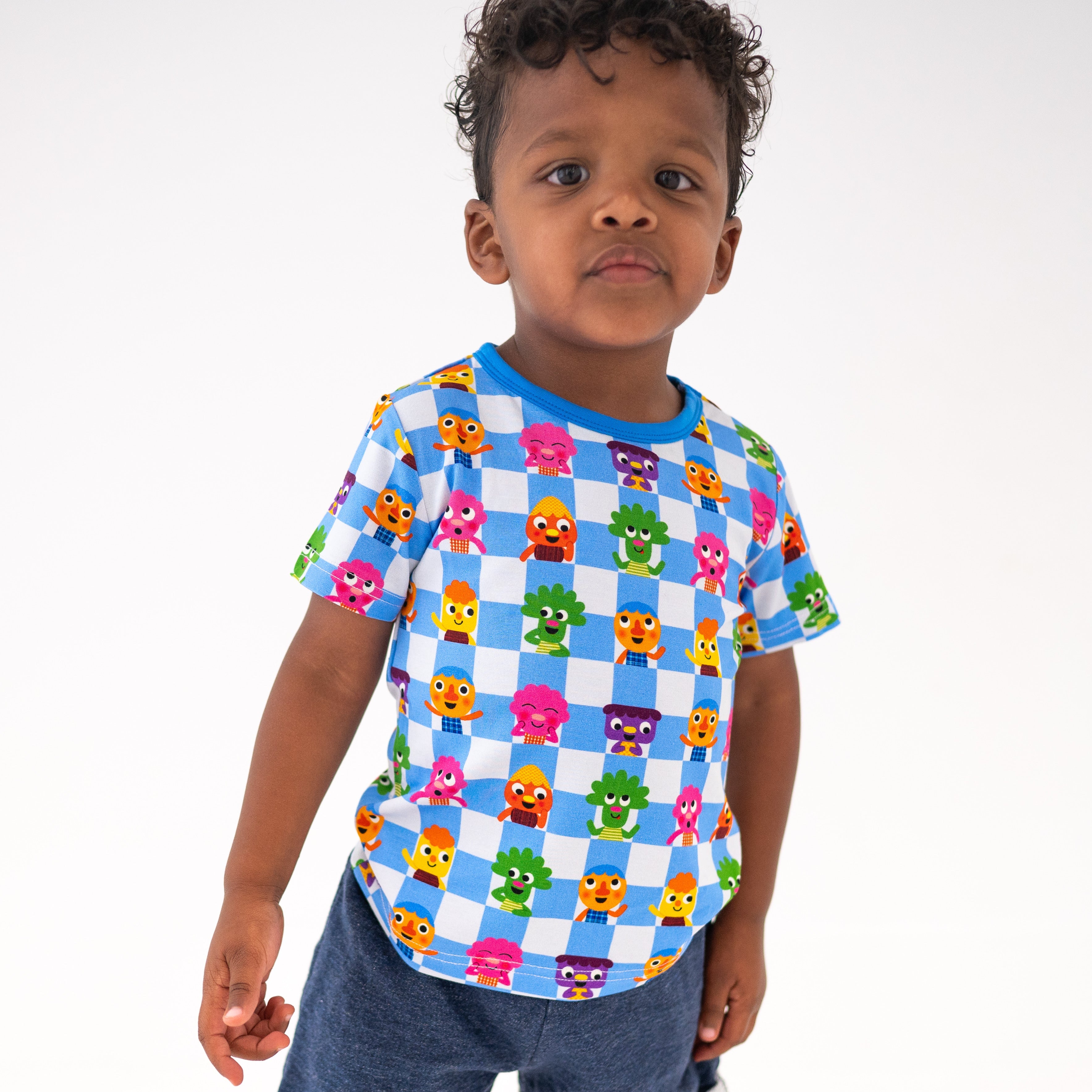 A young boy wears a blue and white checkered t-shirt with cartoon characters.
