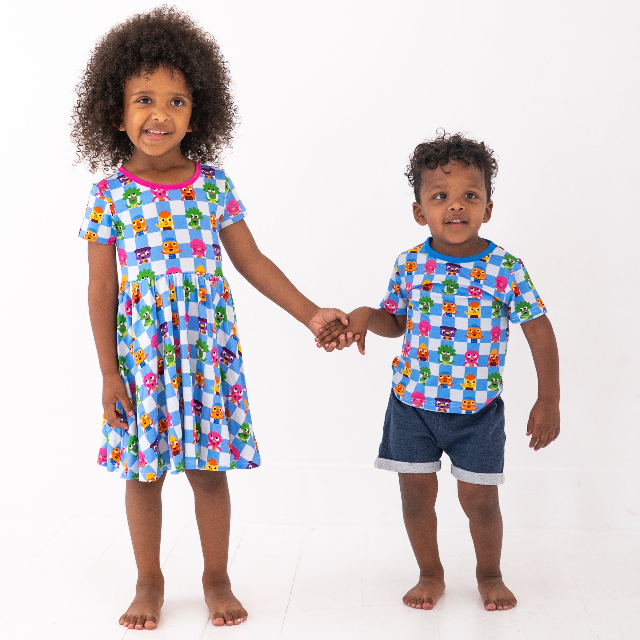 Two children in matching blue checkered outfits with cartoon characters.