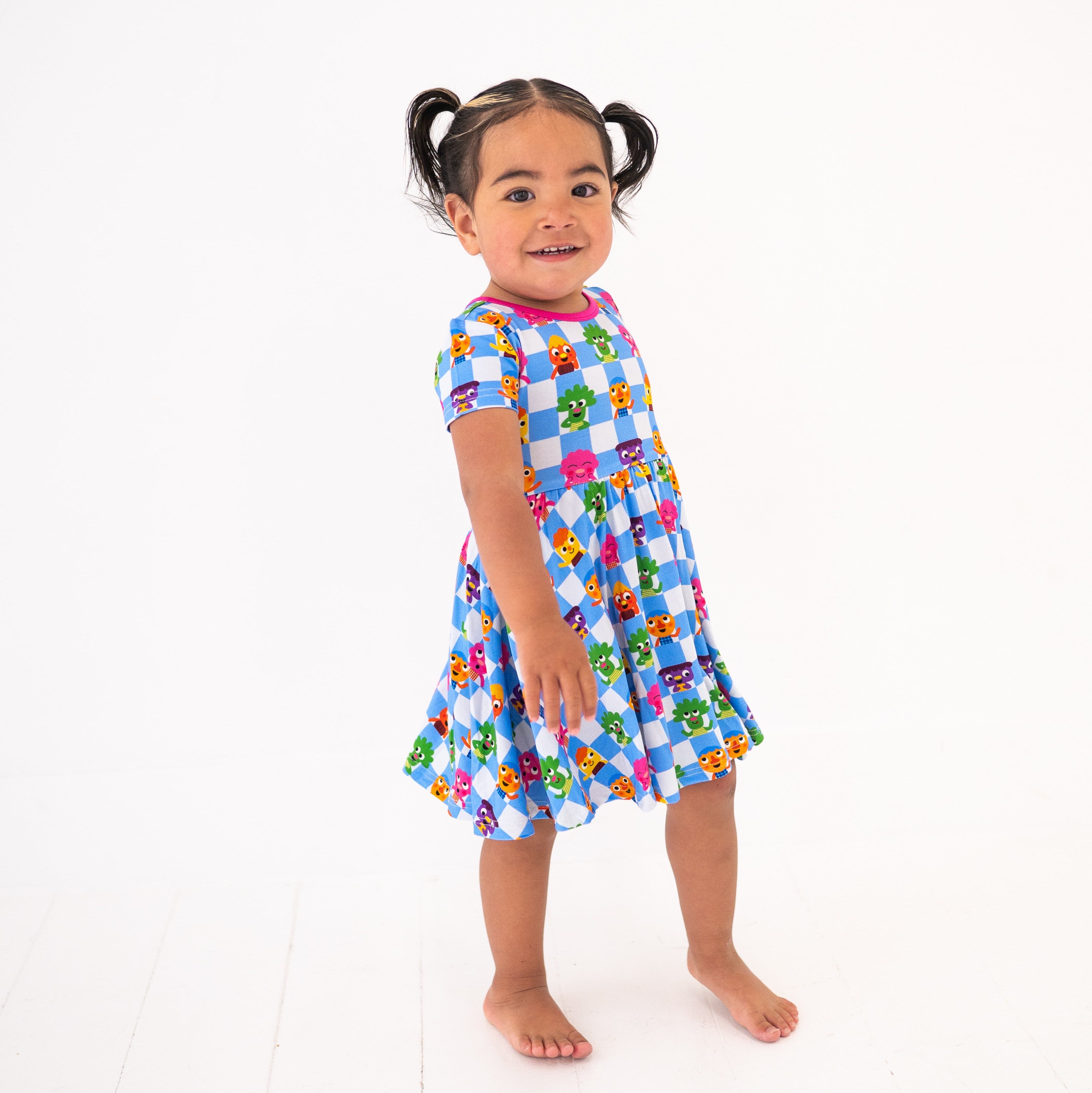 A young girl wears a blue and white checkered dress with cartoon characters.