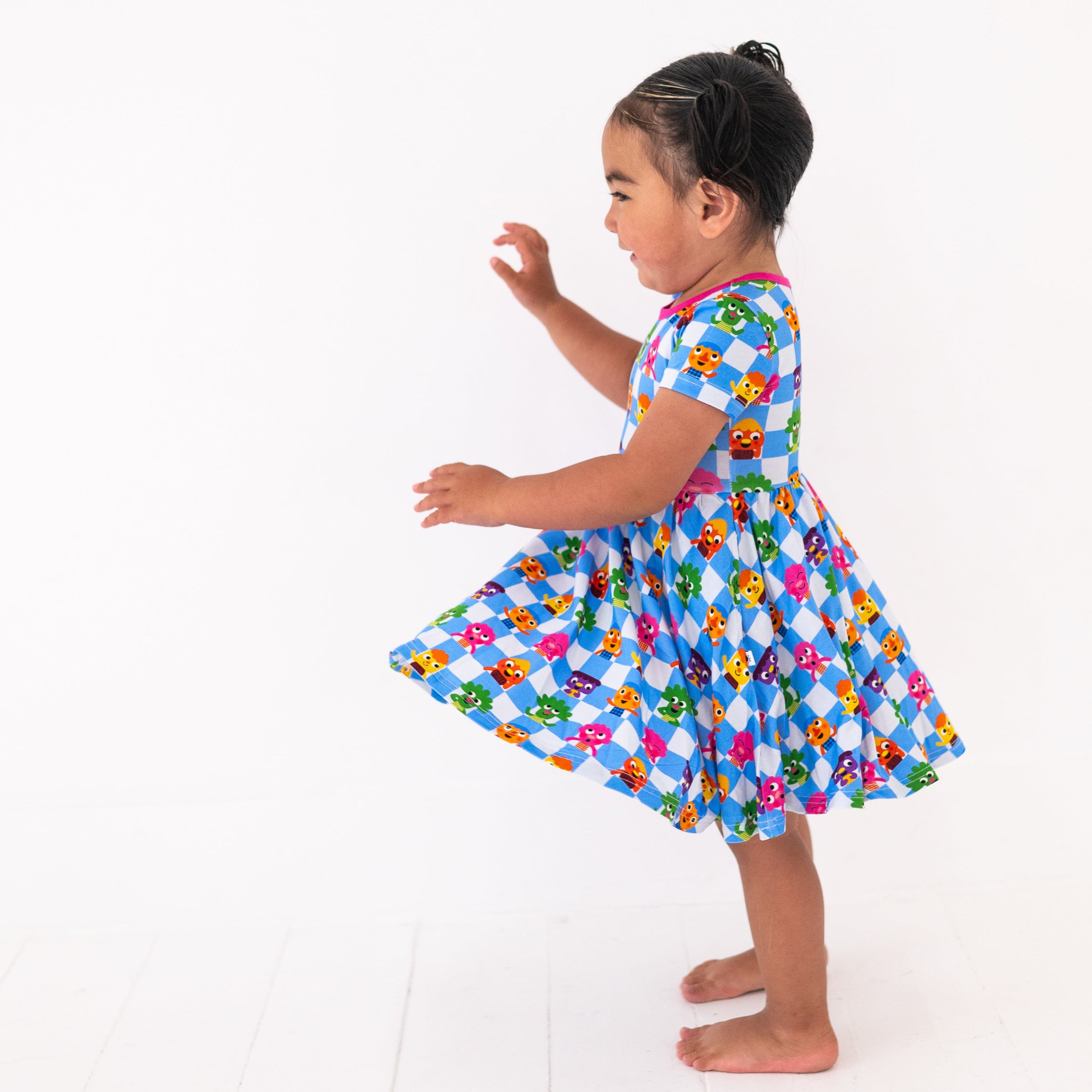 A young girl in a blue and white checkered dress with cartoon characters.