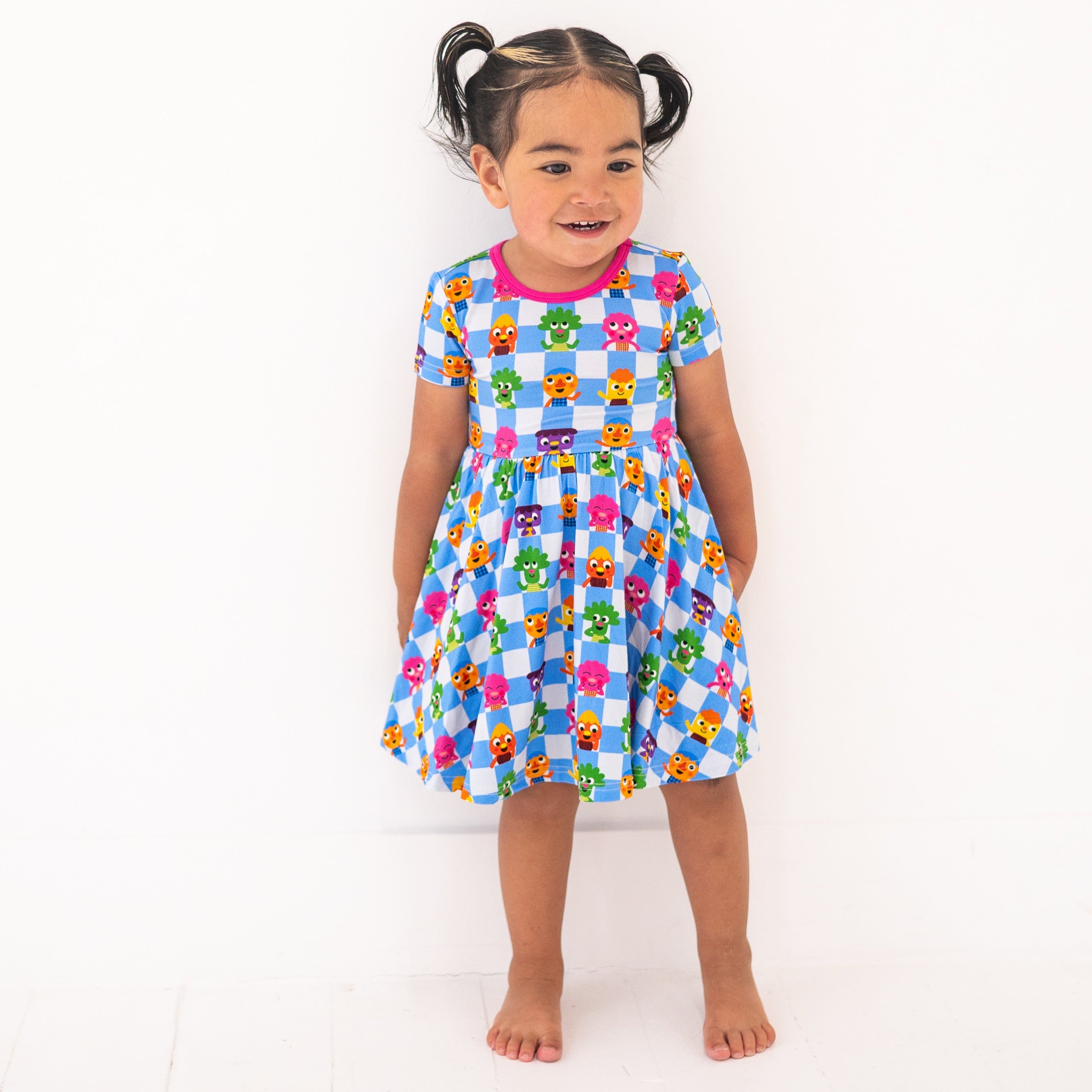 A young girl wears a blue and white checkered dress with cartoon characters.