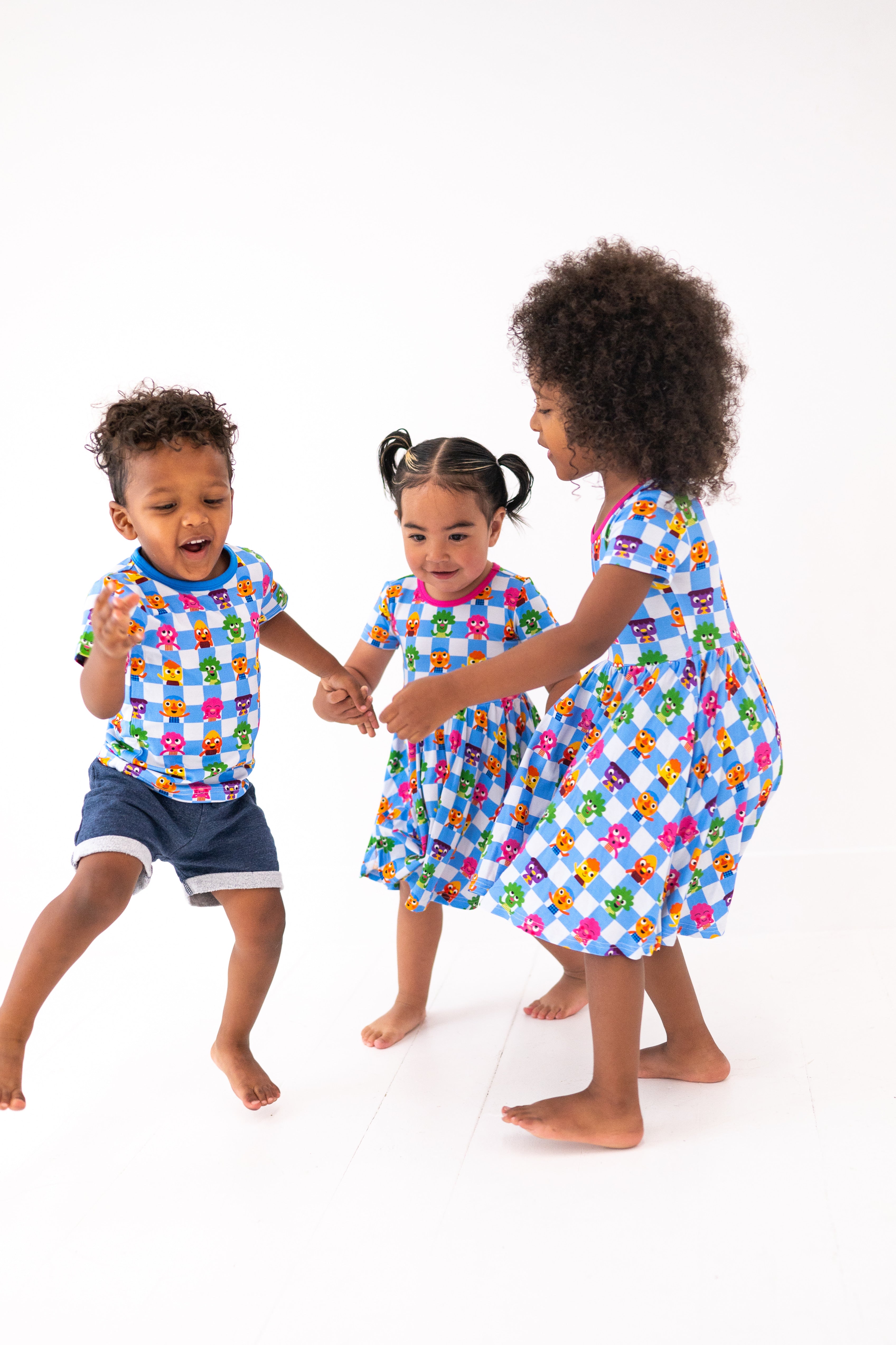 Three children in matching blue checkered outfits with cartoon characters.