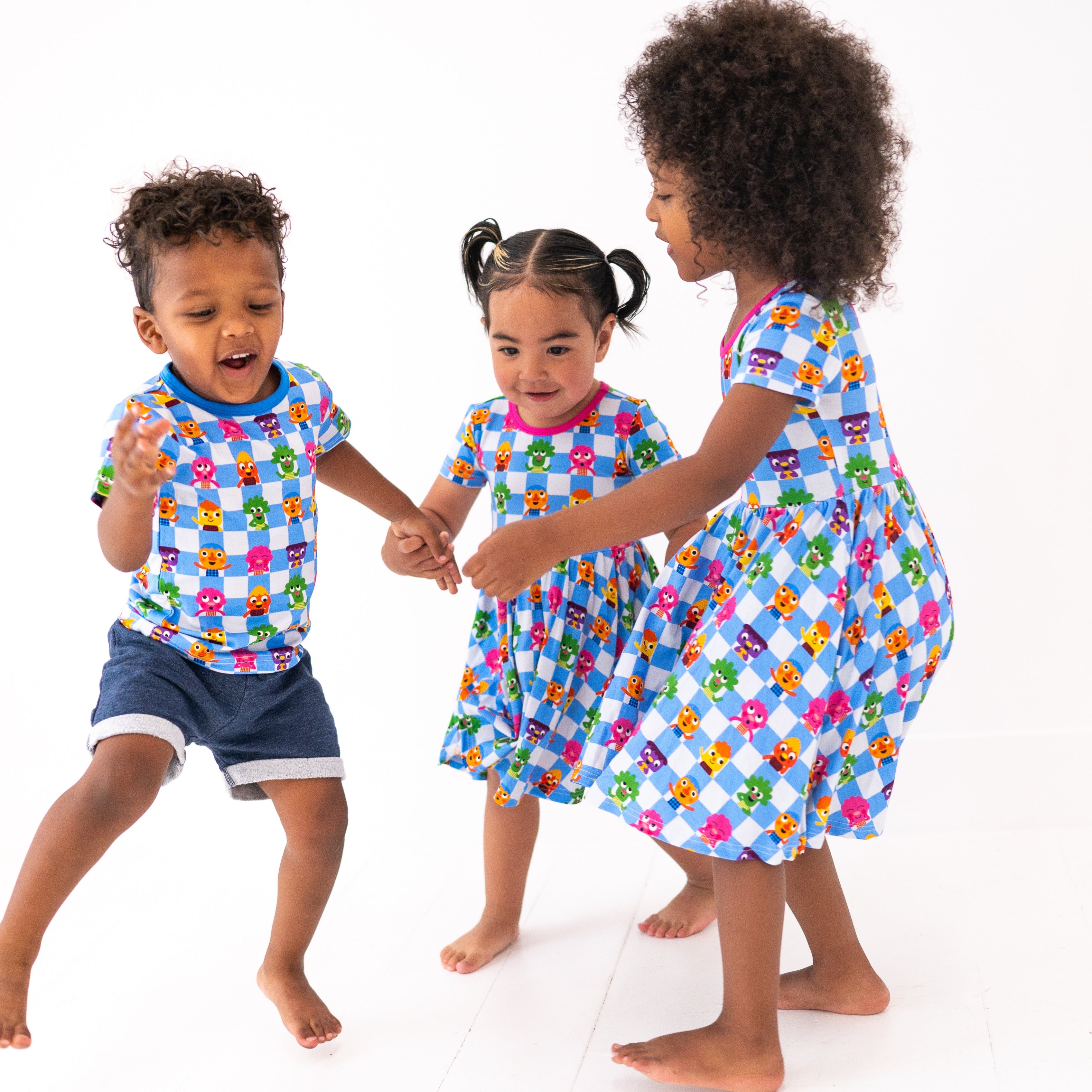 Three children in blue and white checkered dresses with cartoon characters.