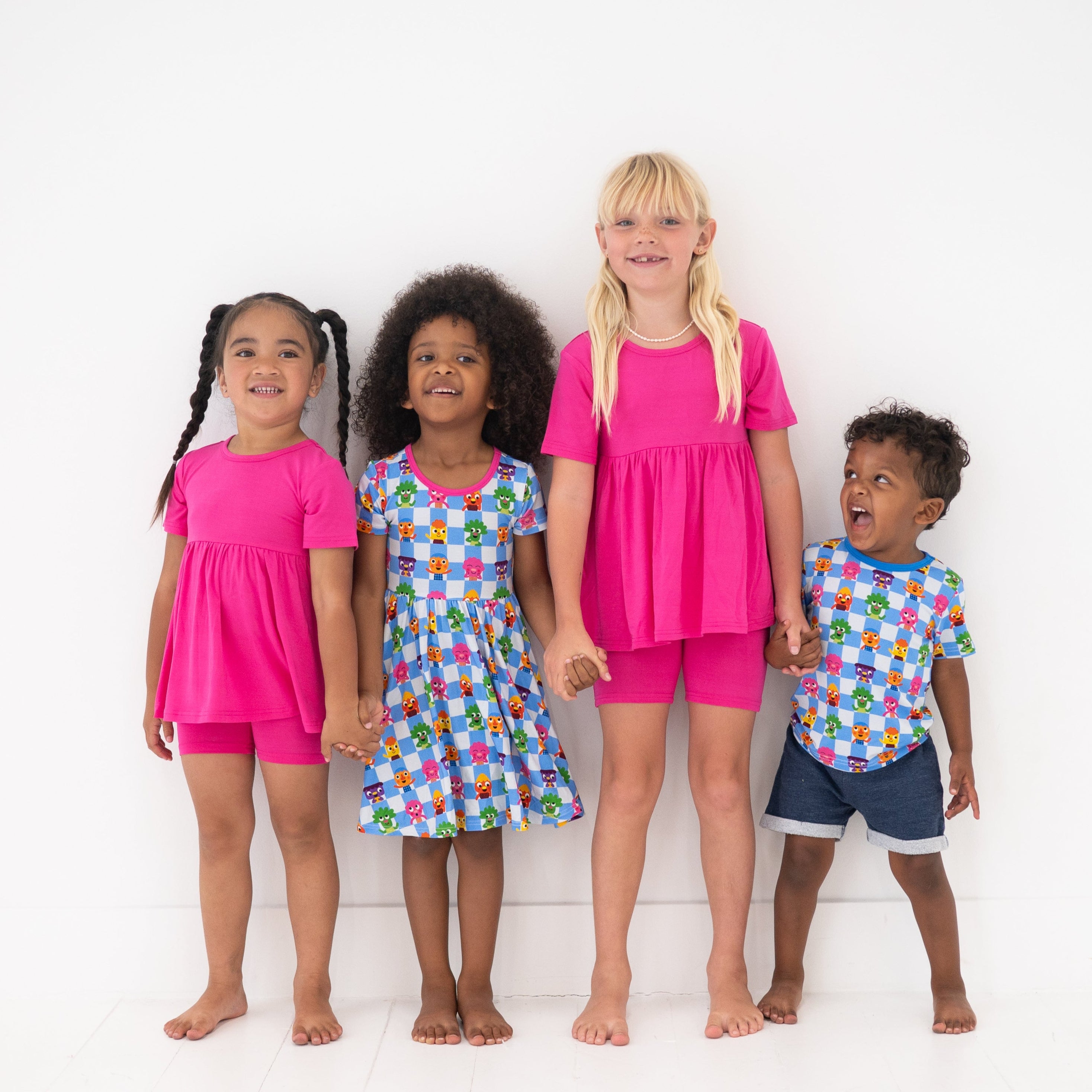 Four children in colorful outfits stand against a white background.