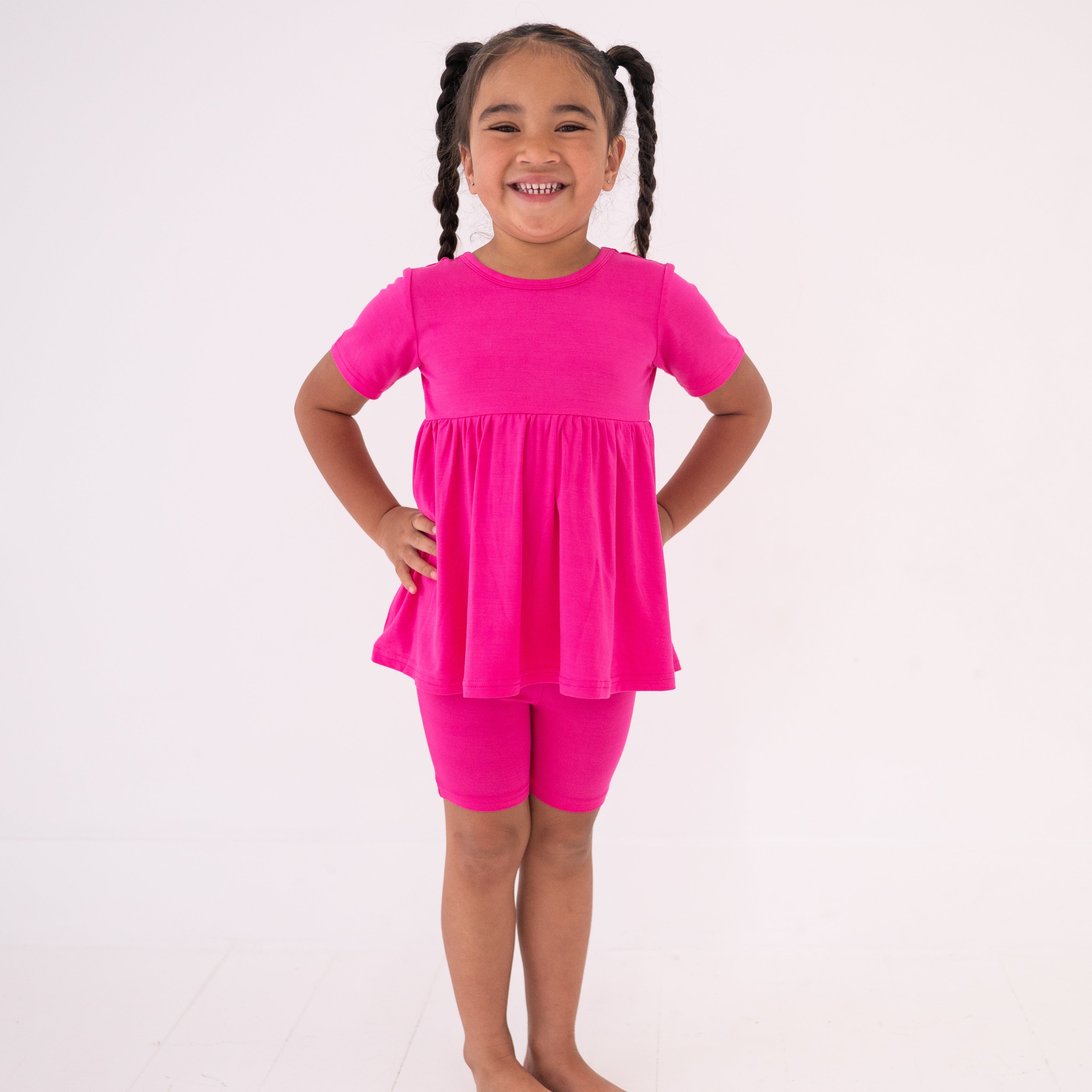 Young girl smiling in pink Luxe Bamboo peplum top with flared hem.