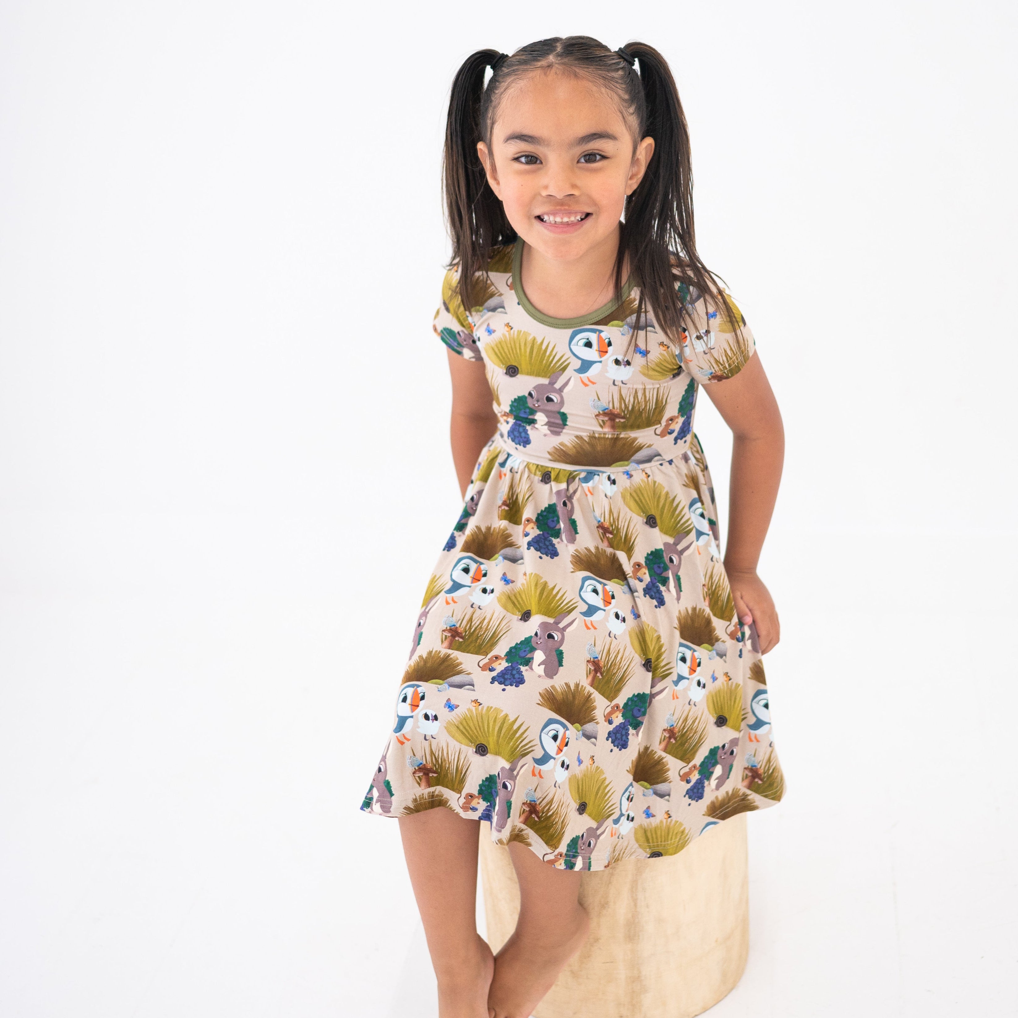 Girl in a Puffin Rock™ bamboo dress with a woodland print.