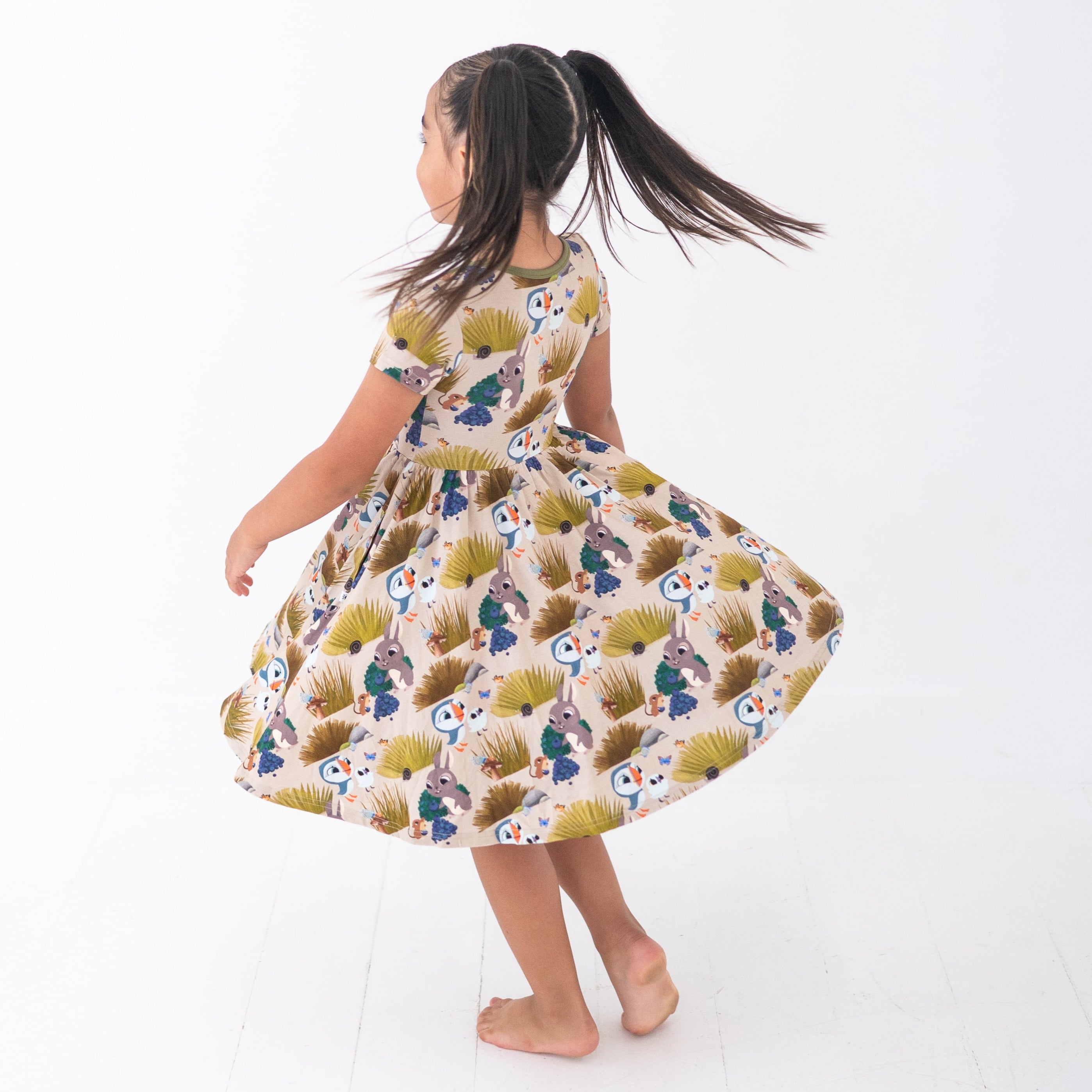 Girl in a Puffin Rock™ bamboo dress with a woodland animal print.