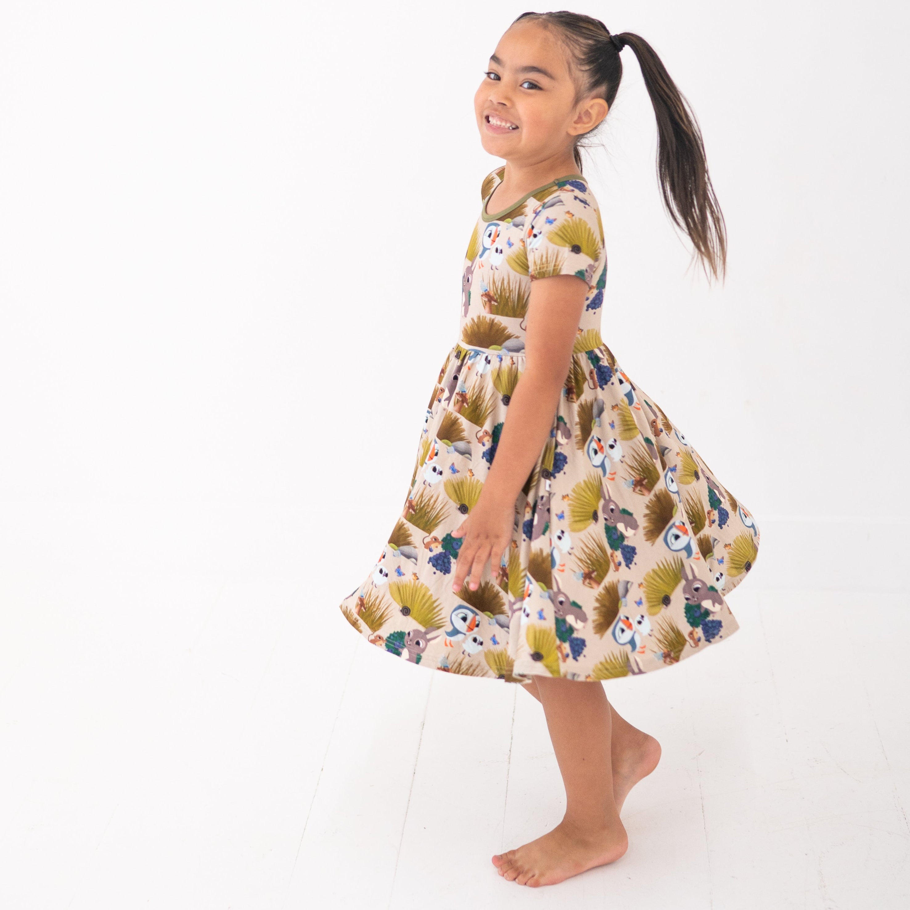A girl in a Puffin Rock™ bamboo dress with a woodland print.