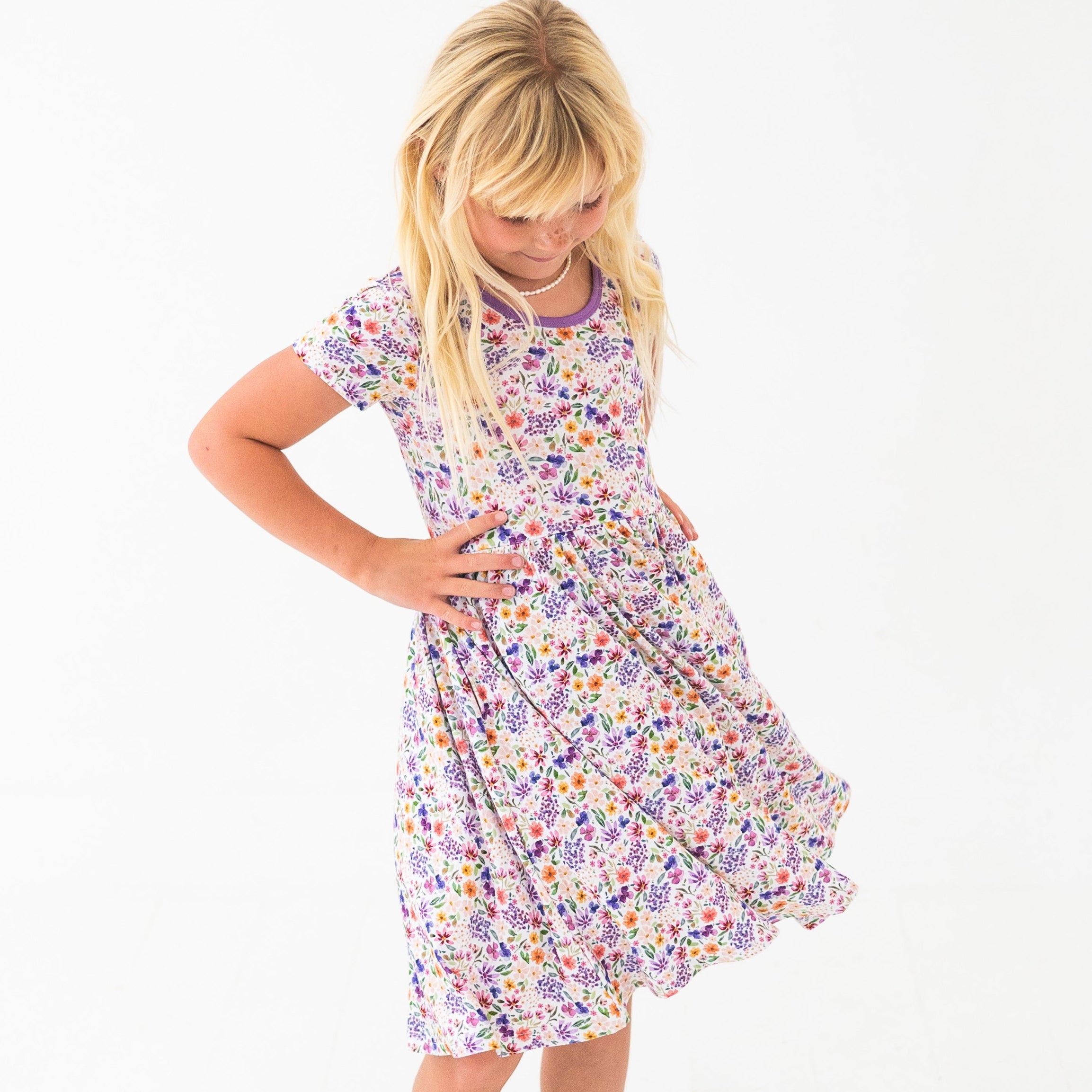A young girl wears a white dress with a floral print.