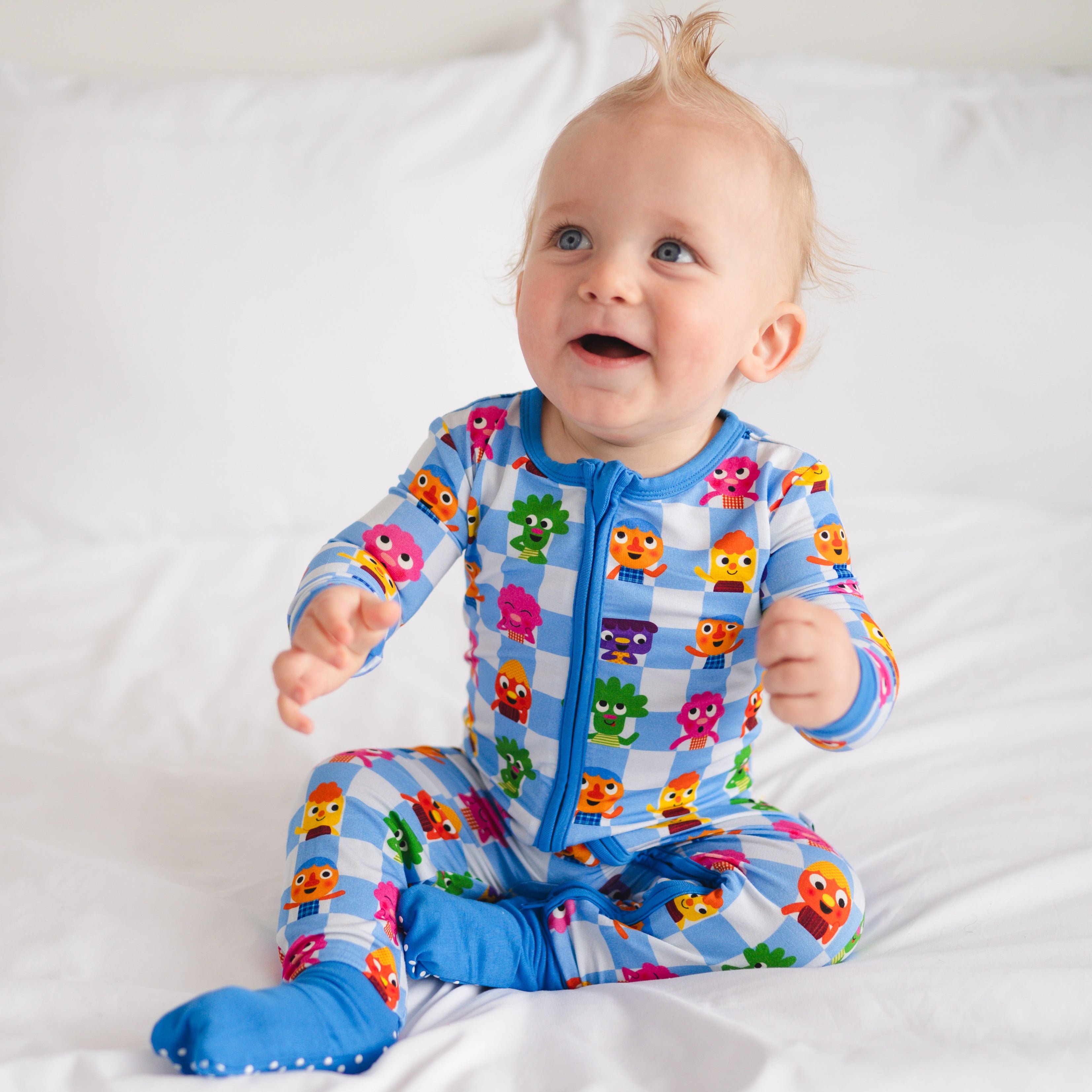 Baby in blue checkered pajamas with cartoon characters.