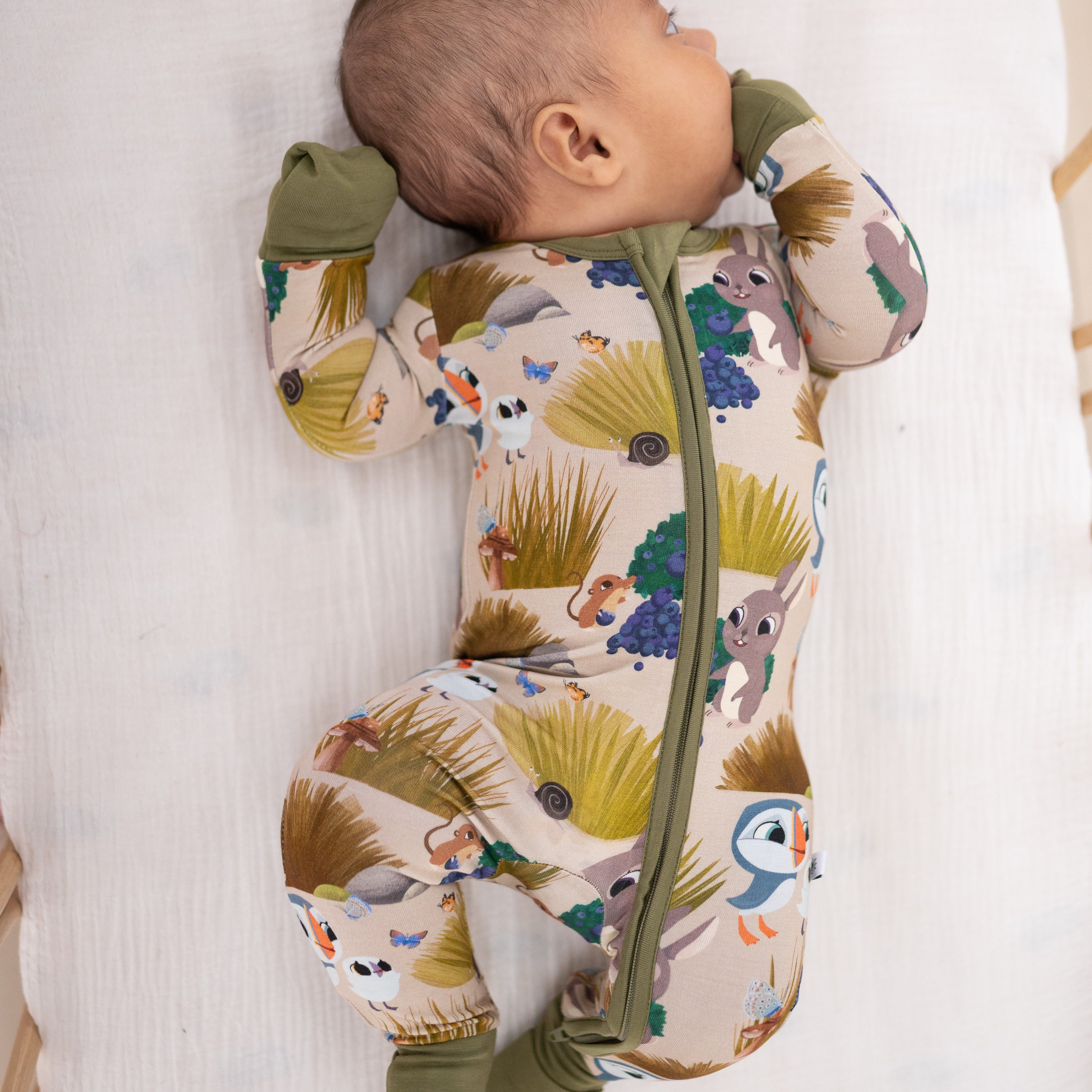A baby wearing a tan bamboo pajama set with a Puffin Rock print.