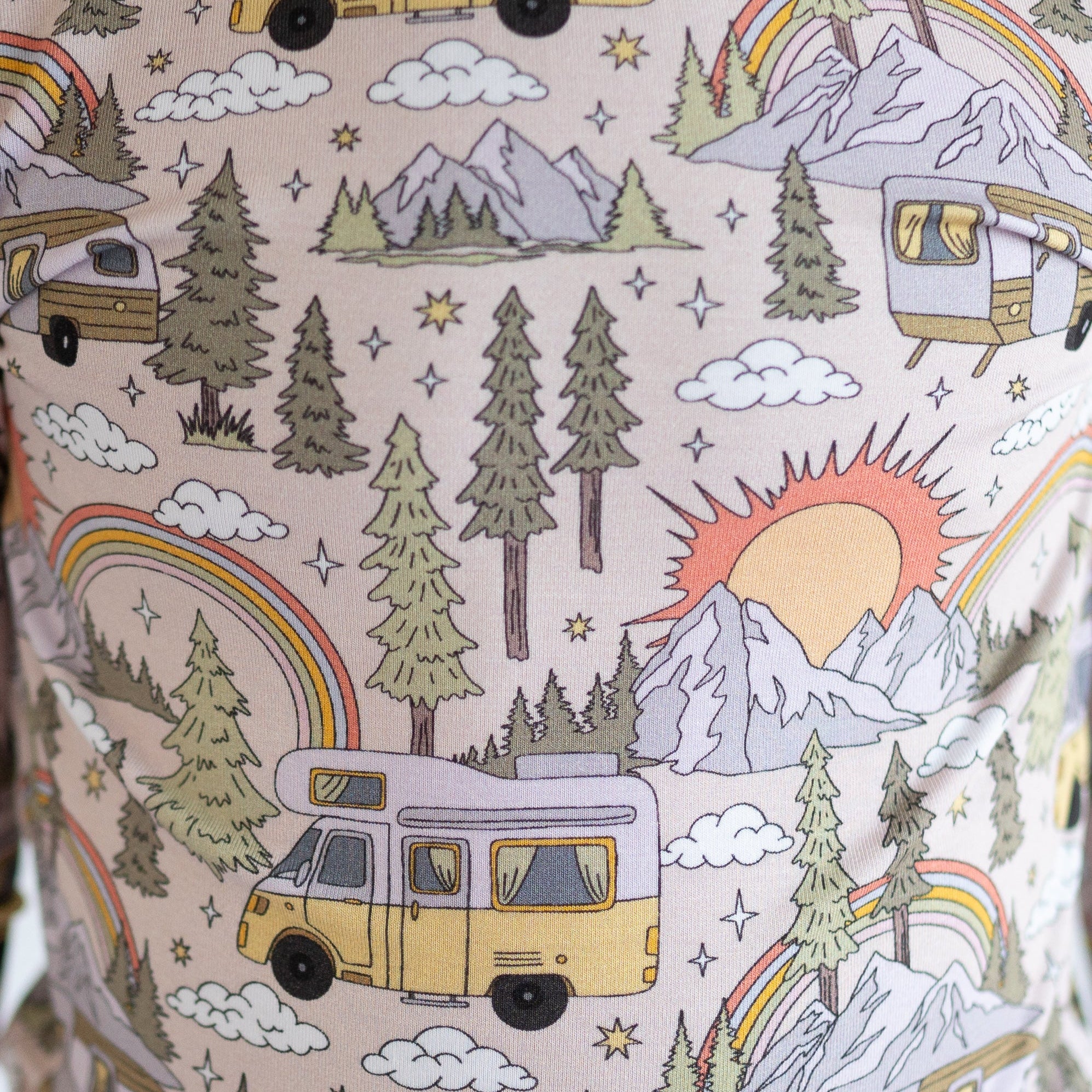 A pink pajama set with a vintage camper, mountains, trees, and rainbow pattern.