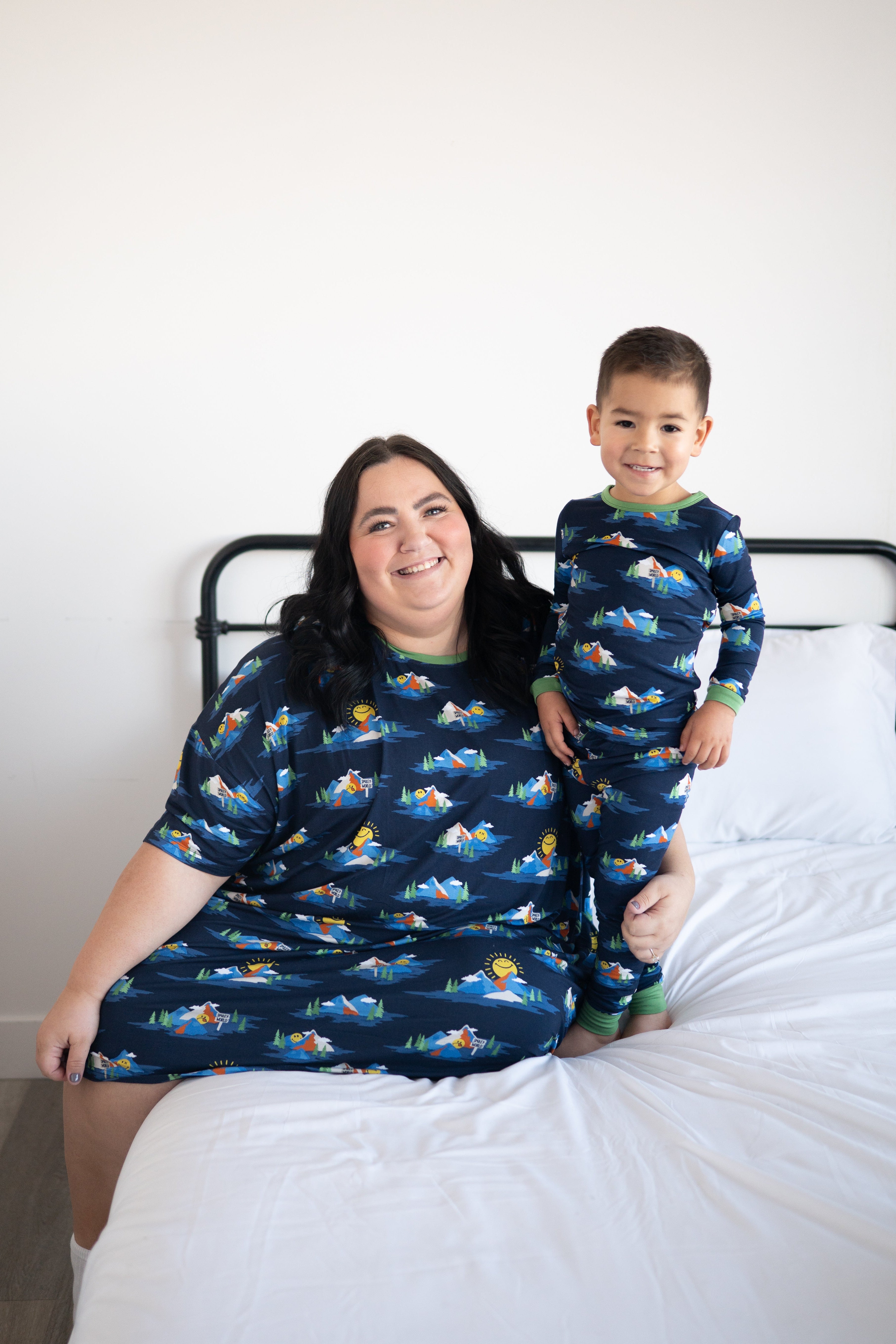 A woman and child in matching navy blue pajamas with a mountain and smiley face print.