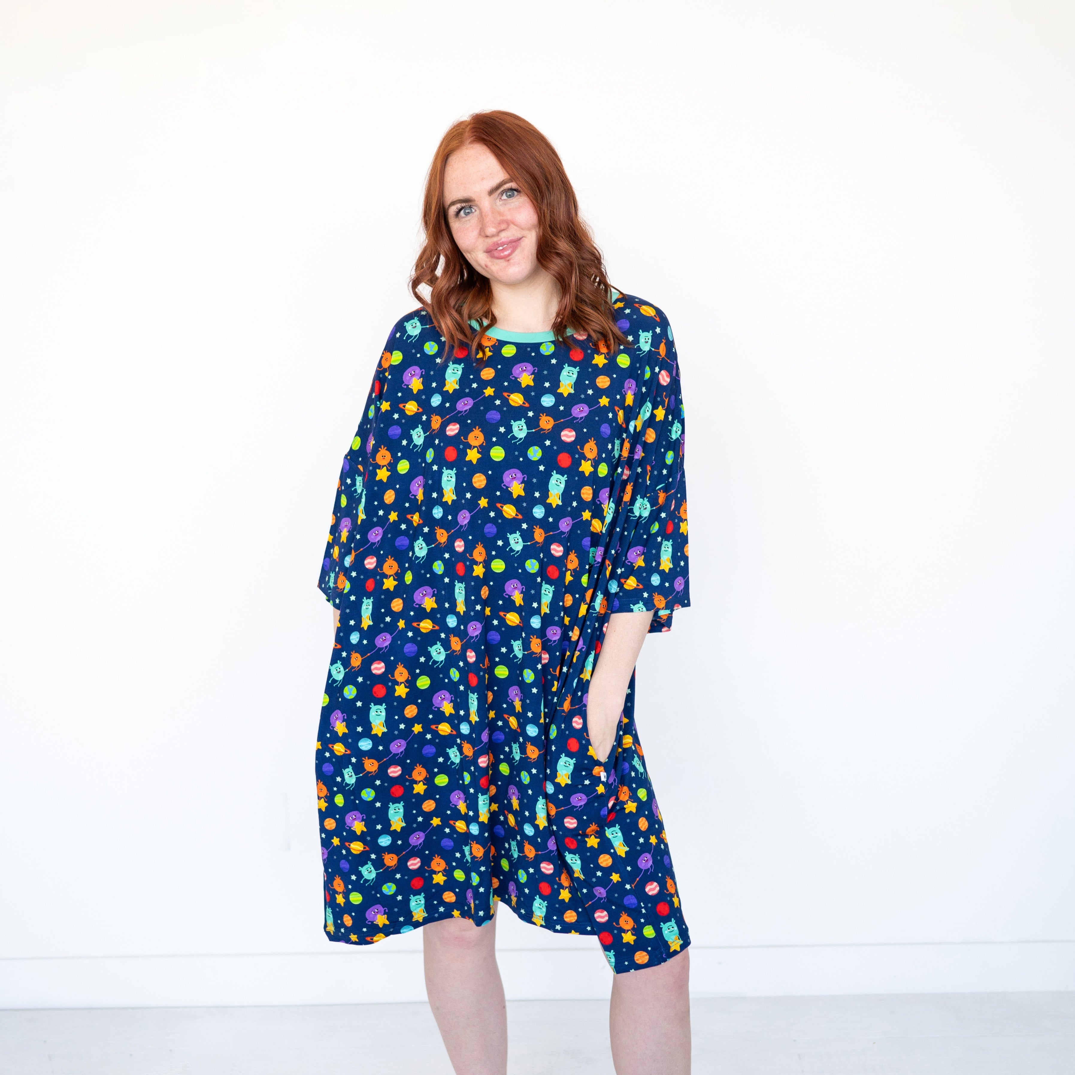 A woman models a navy blue sleep tee with a colorful space-themed print.