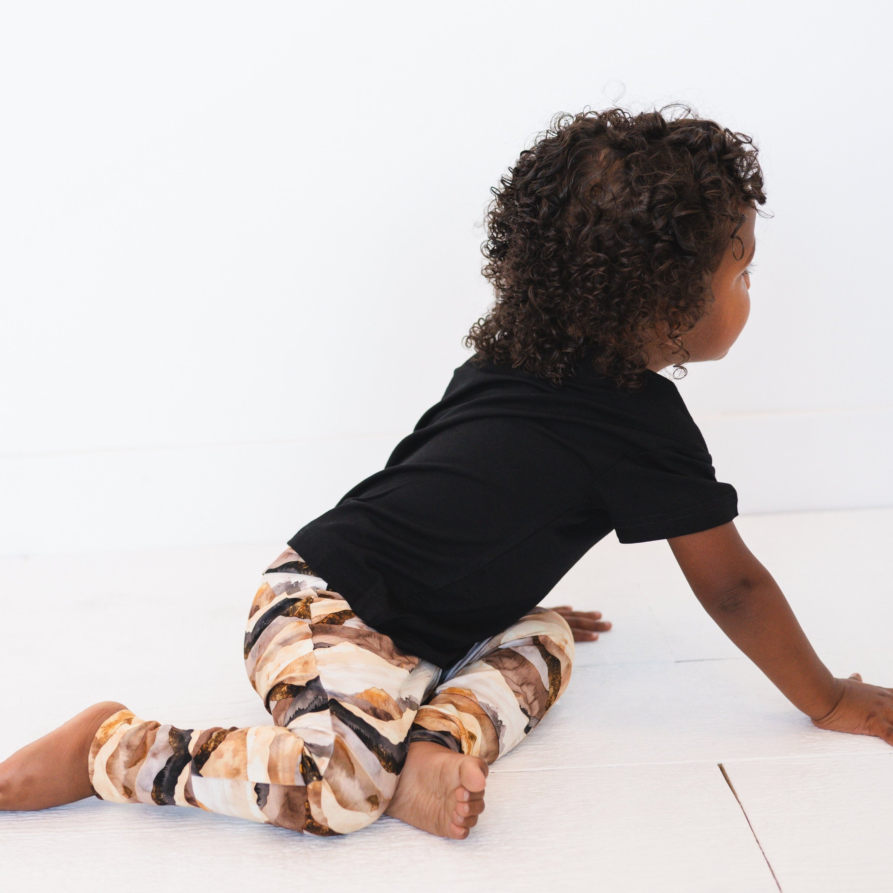 A child wearing black top and mountain range print bamboo pants.