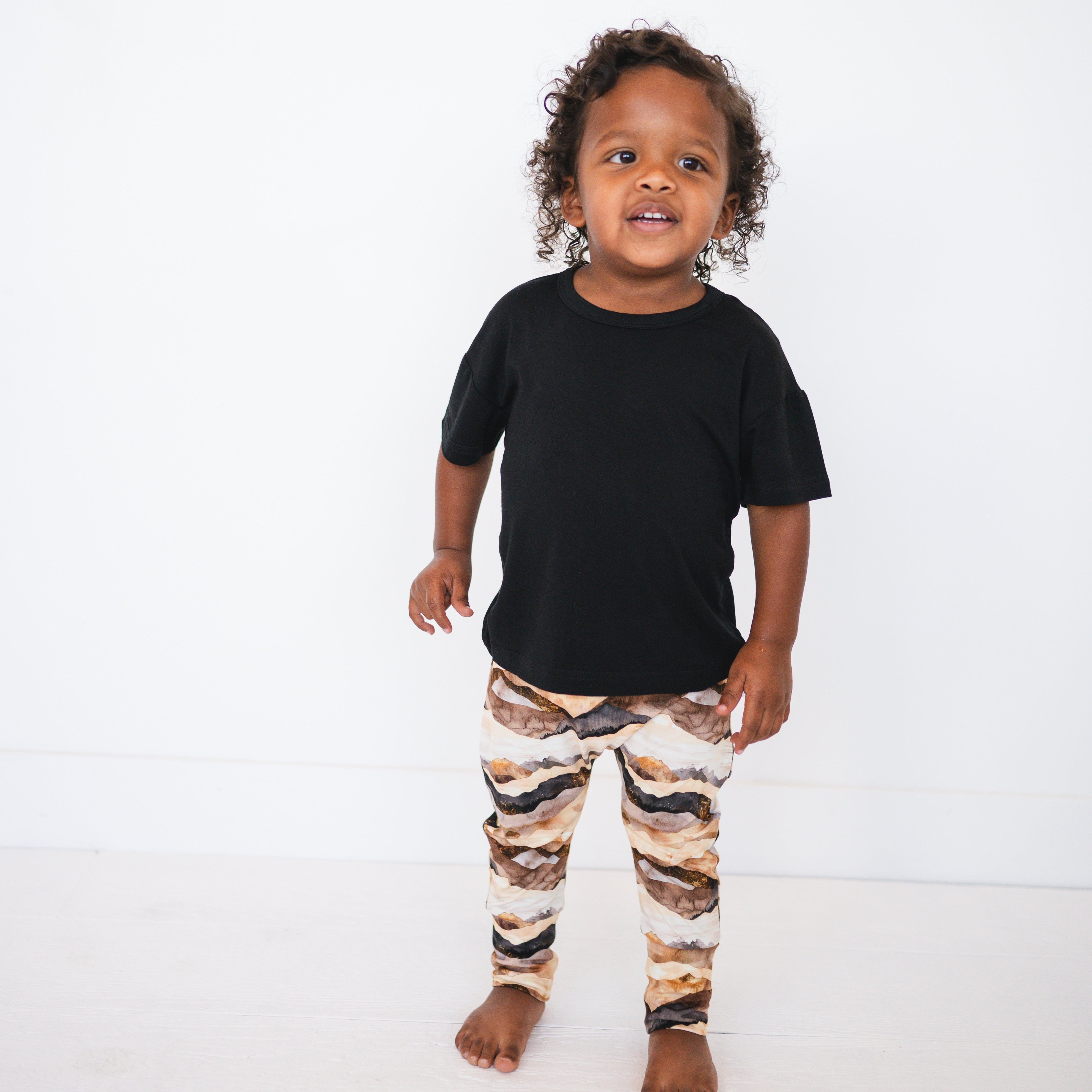 Toddler in black t-shirt and mountain range print bamboo pants.