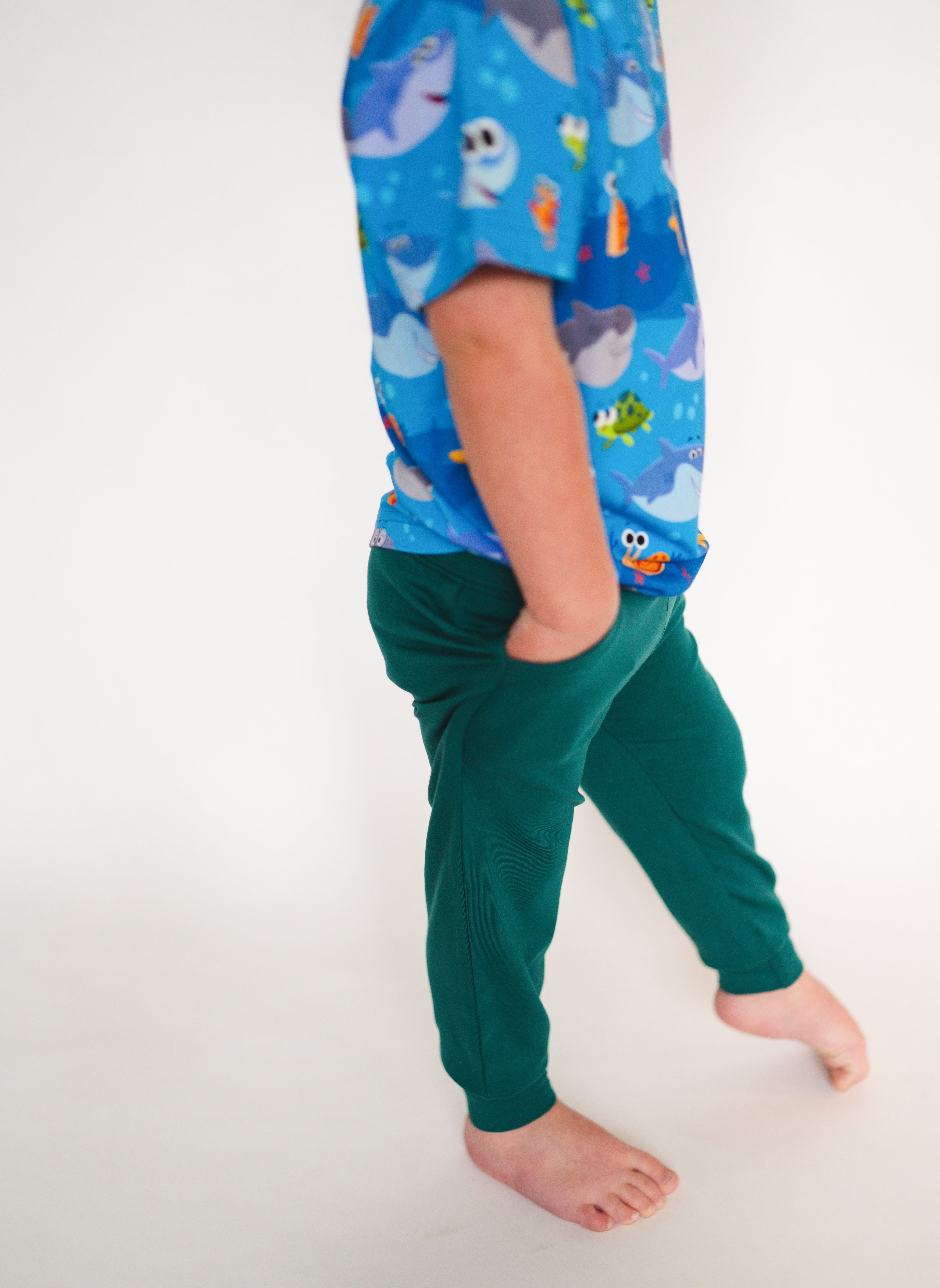 A child wears green joggers and a blue shirt with a duck pond print.