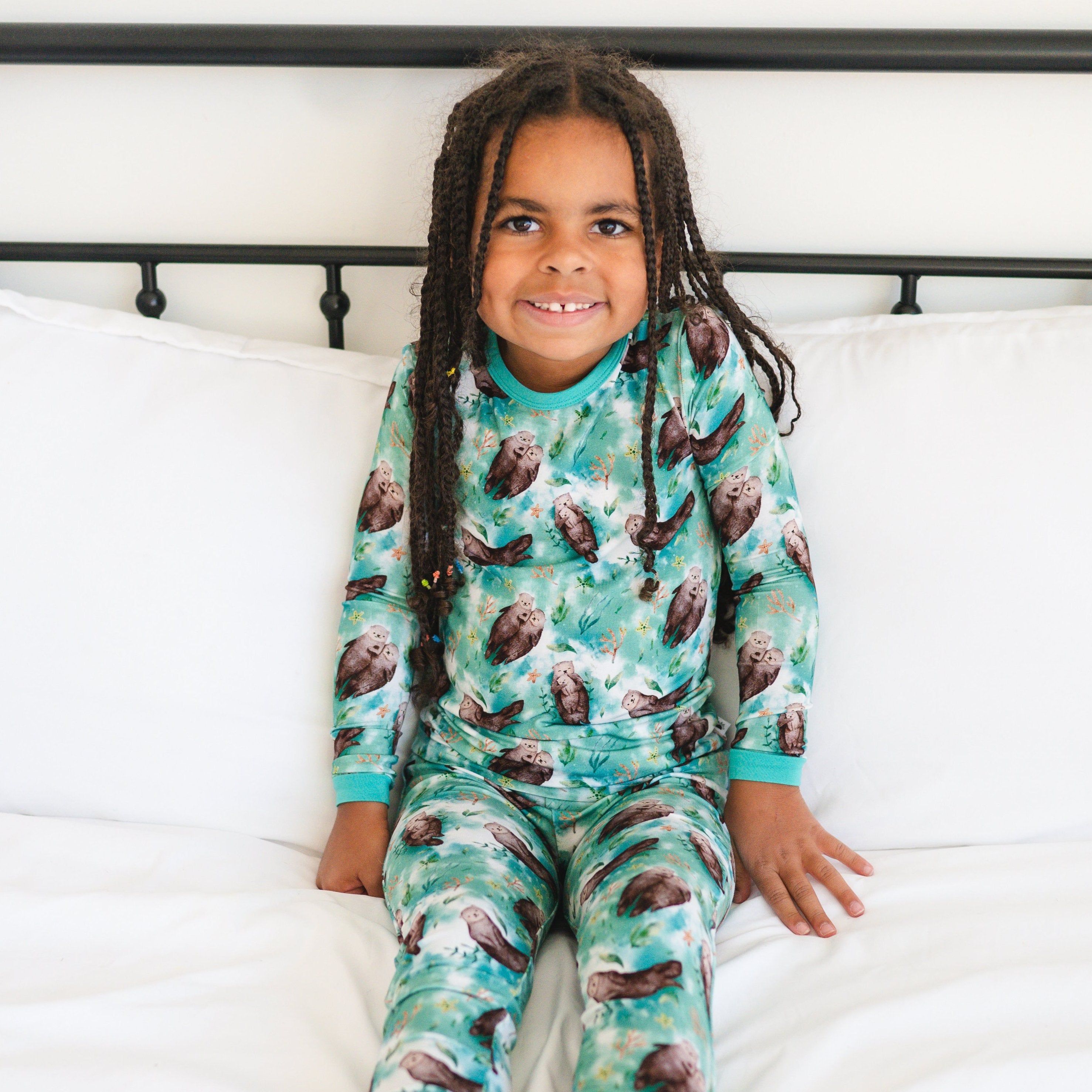 A young girl smiles while wearing a teal pajama set with an otter print.
