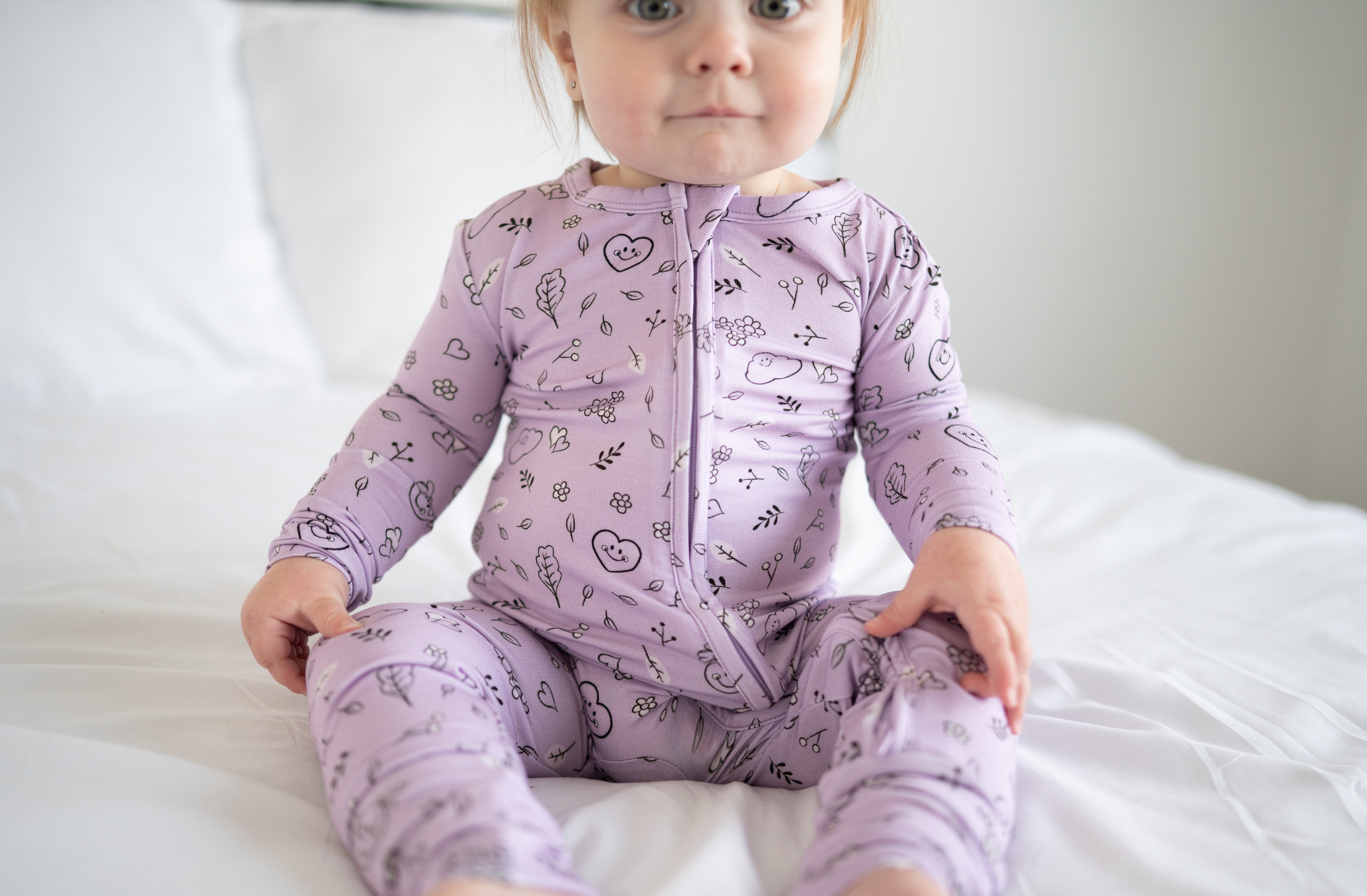 A baby wearing a lilac bamboo pajama set with a doodle print.