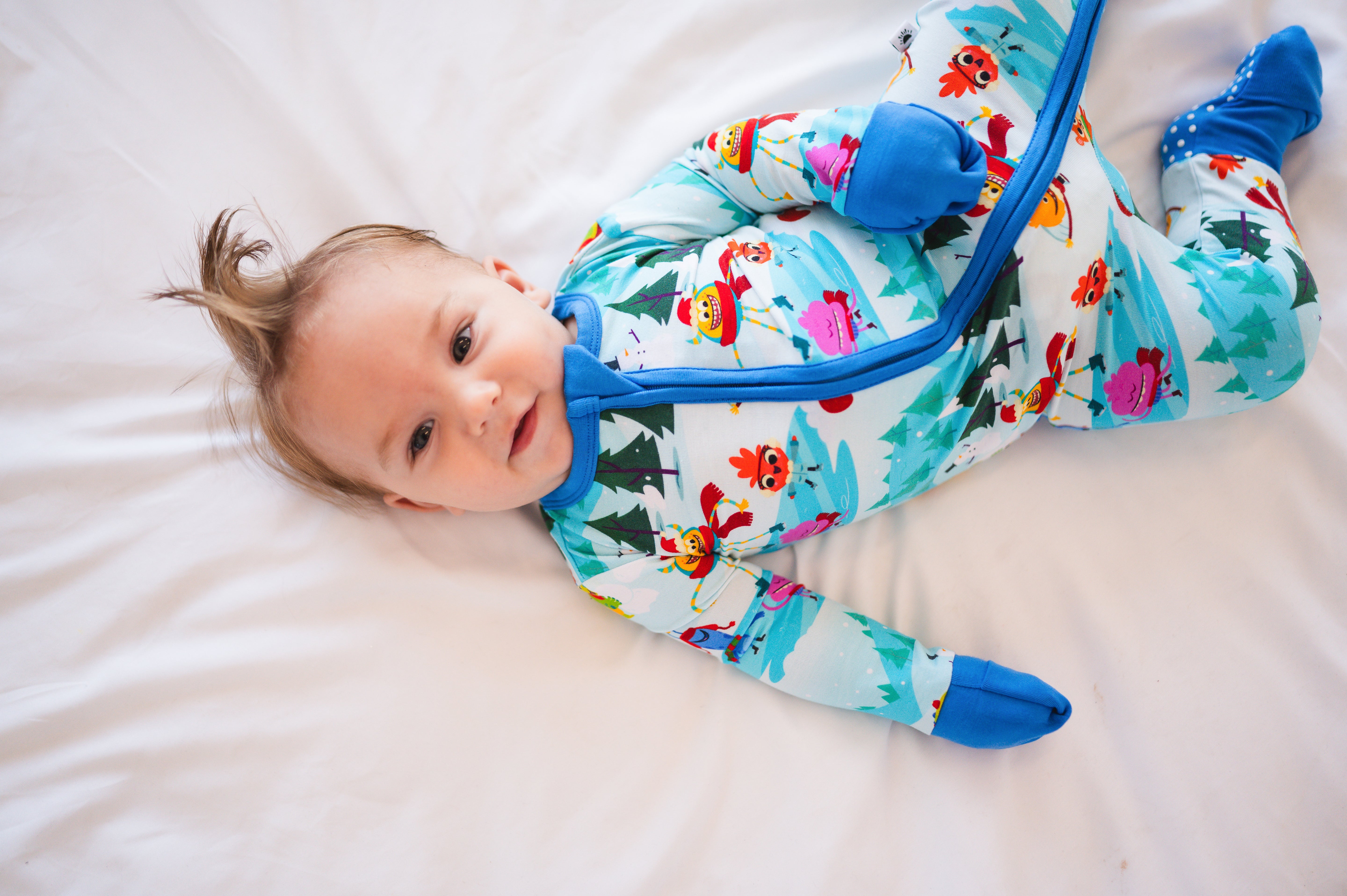 Baby in a light blue bamboo pajama set with a snow-themed print.