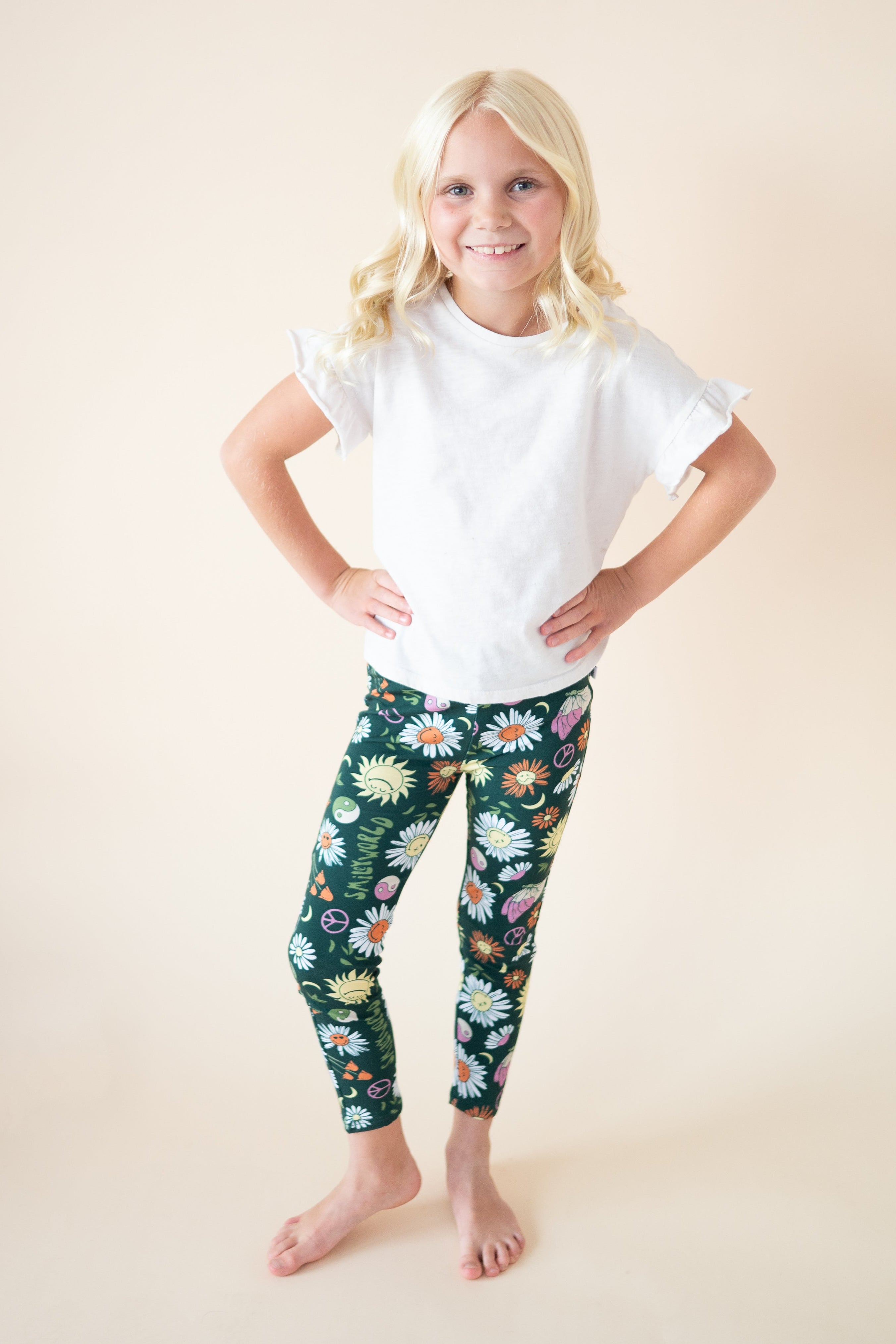 Girl wearing white t-shirt and green leggings with SmileyWorld floral print.