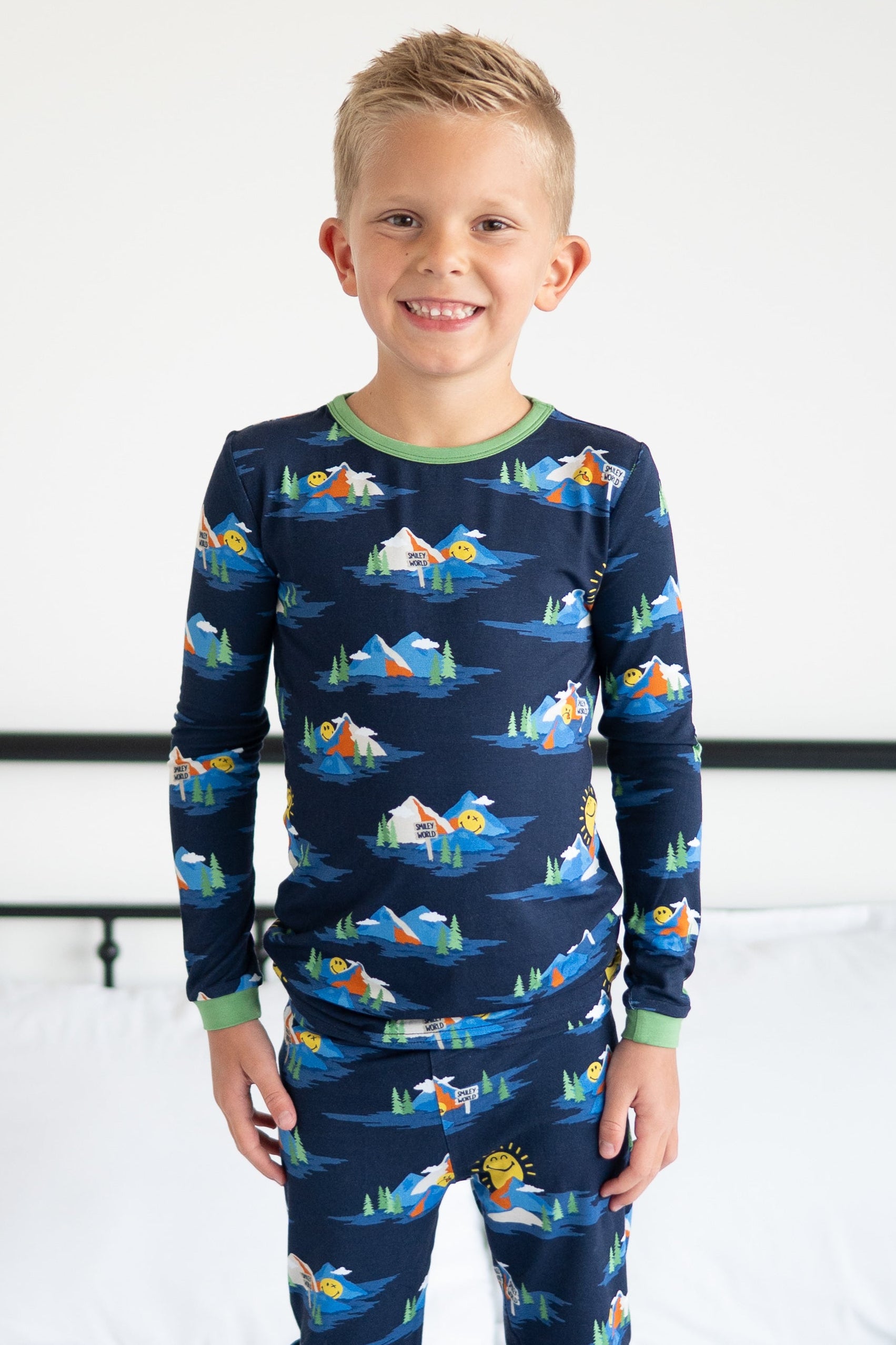 Boy in navy blue pajamas with a mountain and smiley face print.