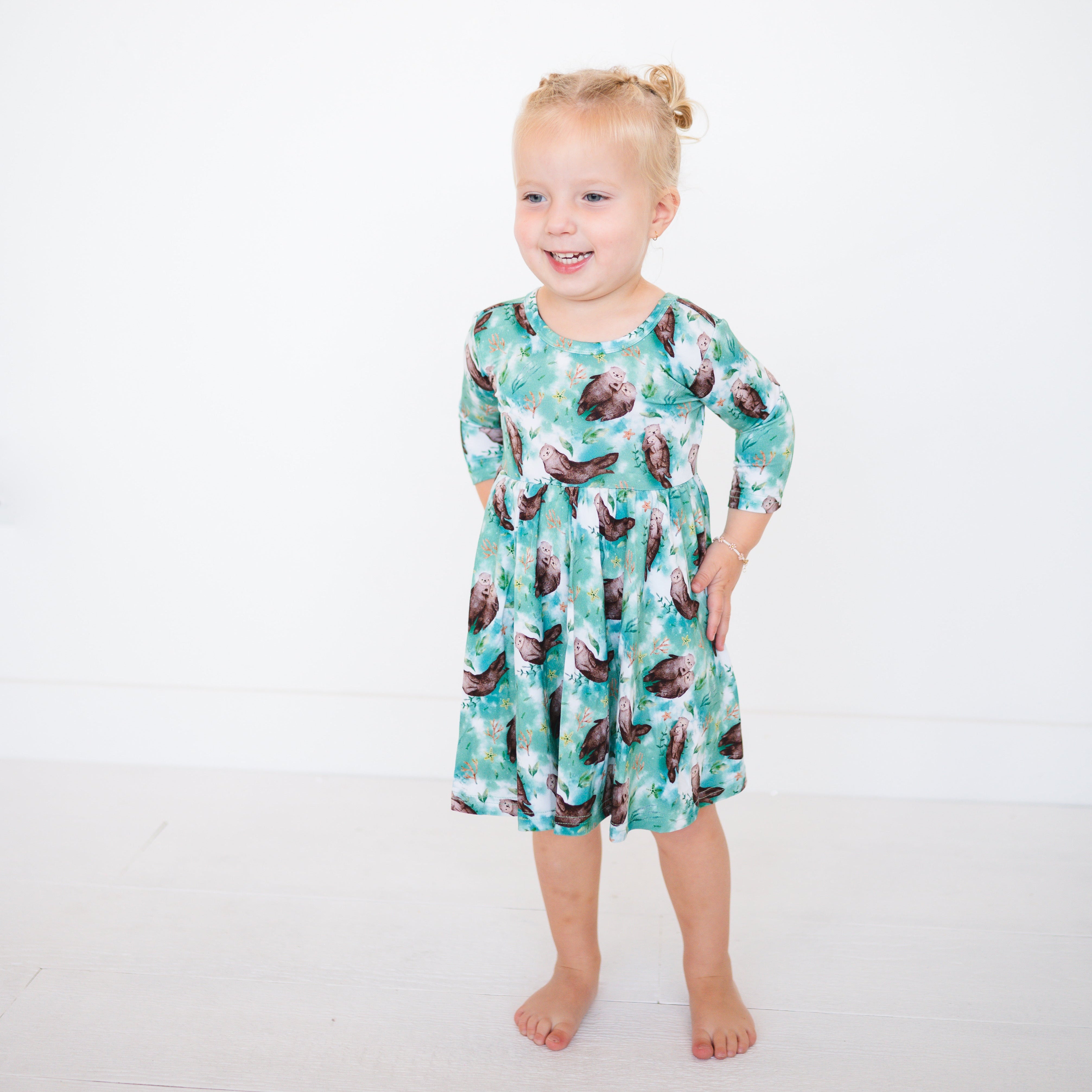 A young girl wears a teal dress with an otter print.