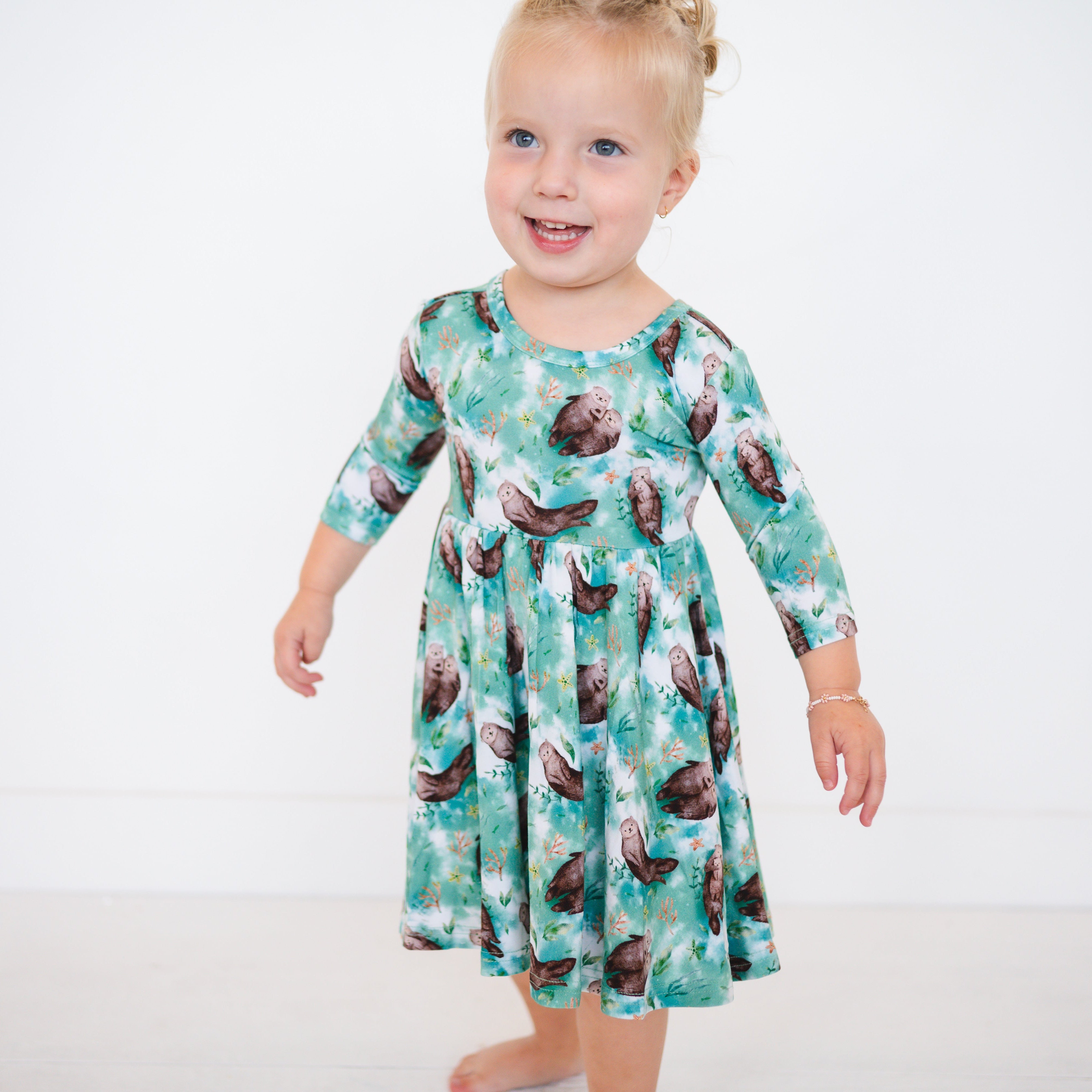 A young girl wears a green dress with an otter print.
