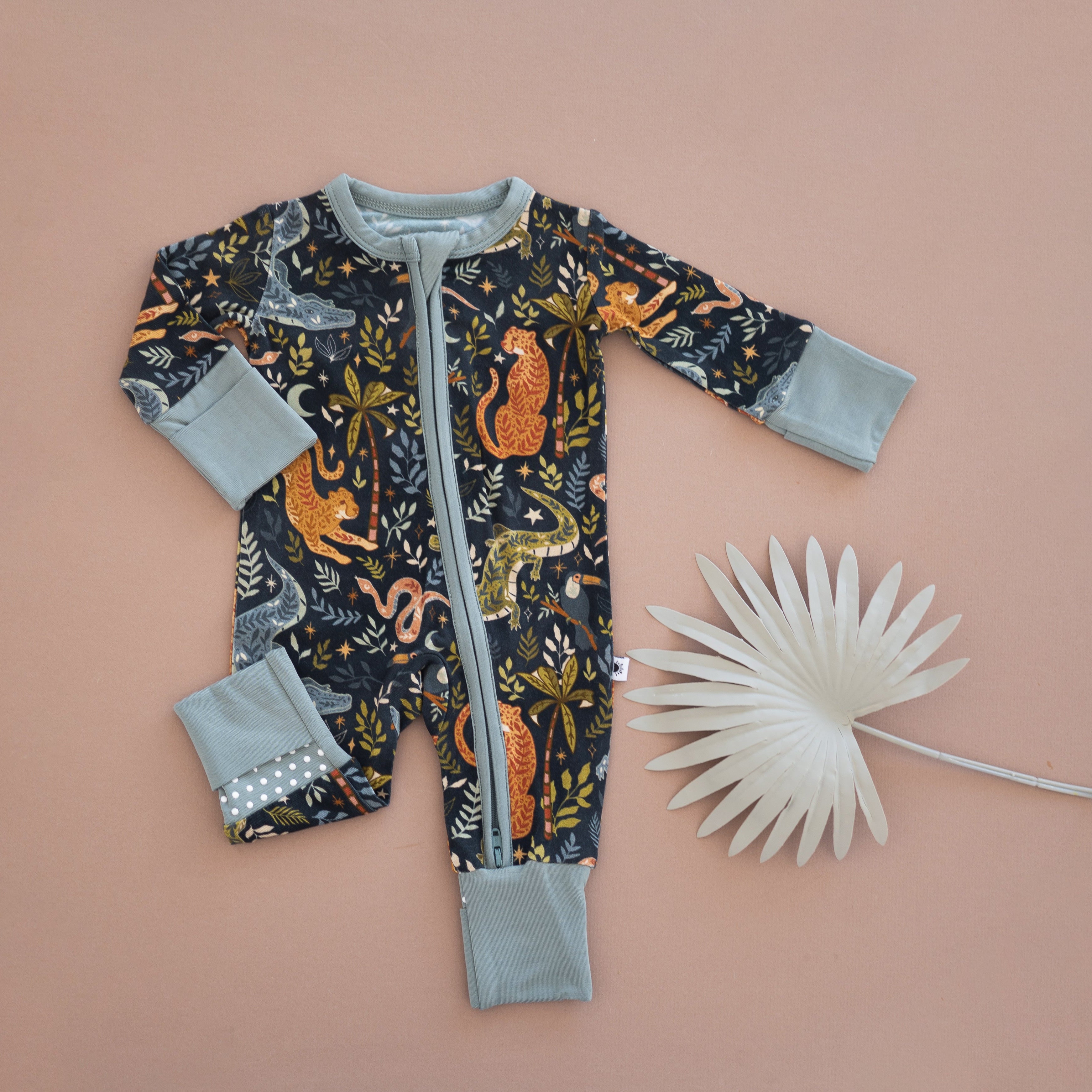 A dark blue baby pajama set with a jungle print and light blue cuffs.