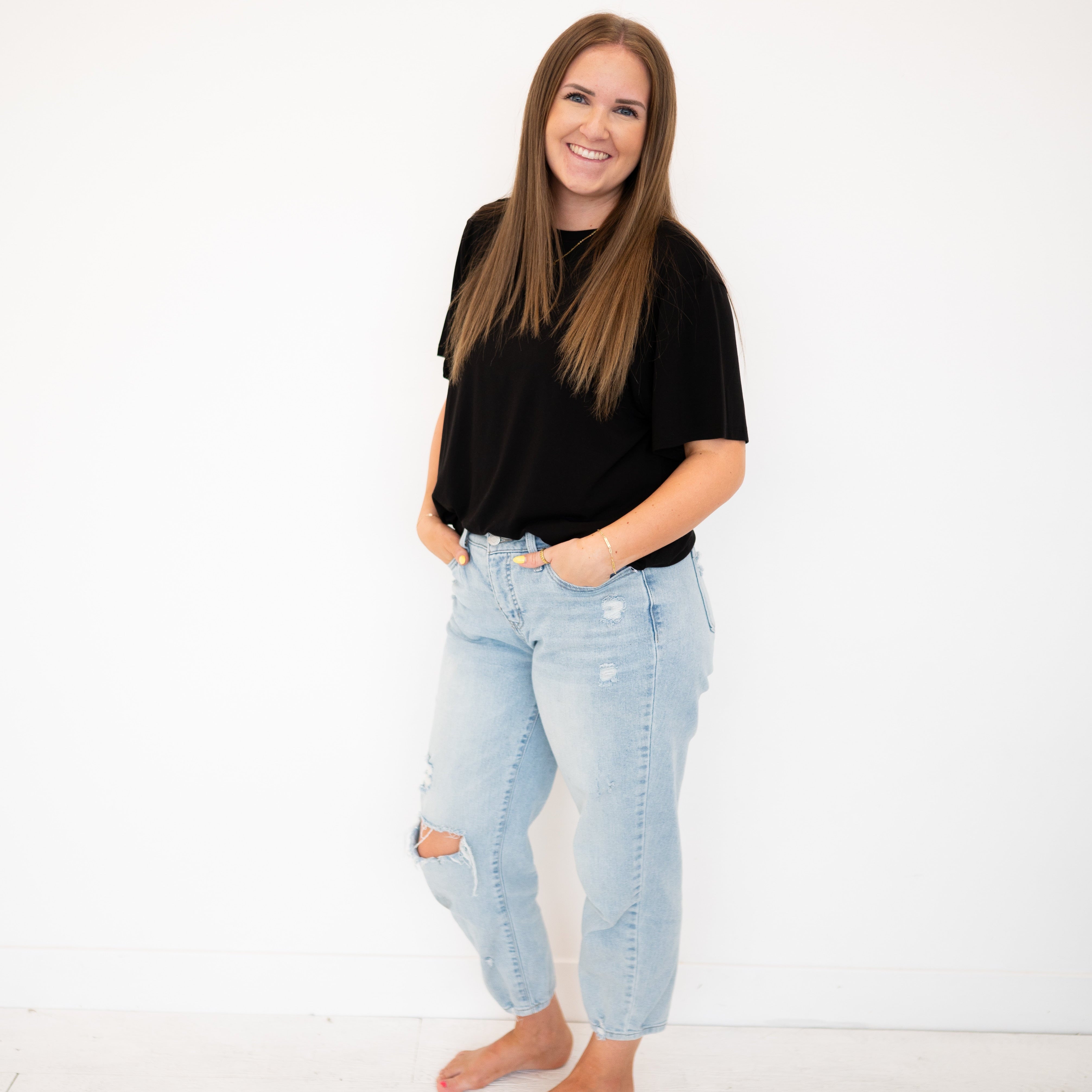 Woman in black oversized bamboo tee and light wash ripped jeans.